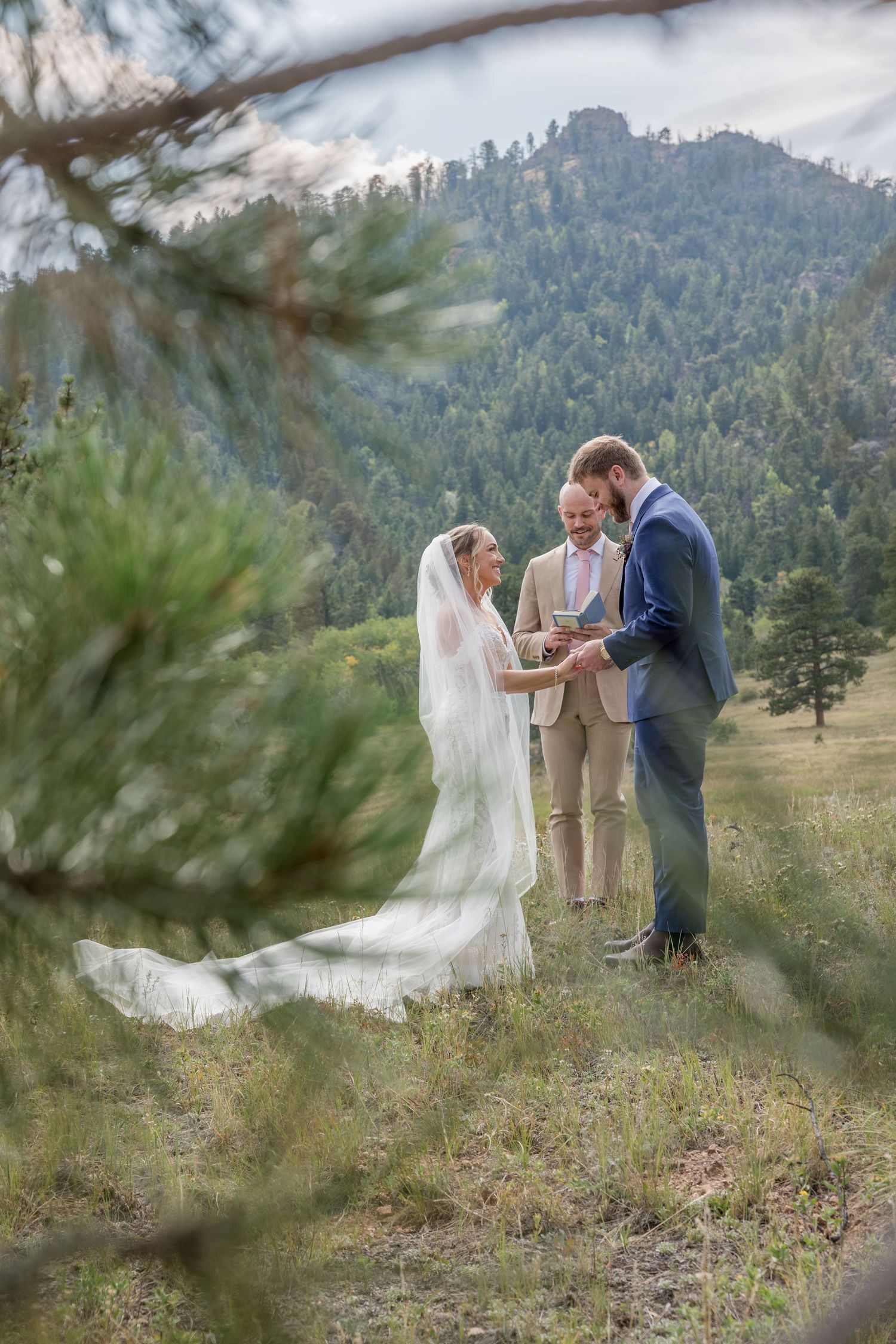 A couple shares their first look moment during an outdoor mountain wedding ceremony in a scenic pine forest setting.