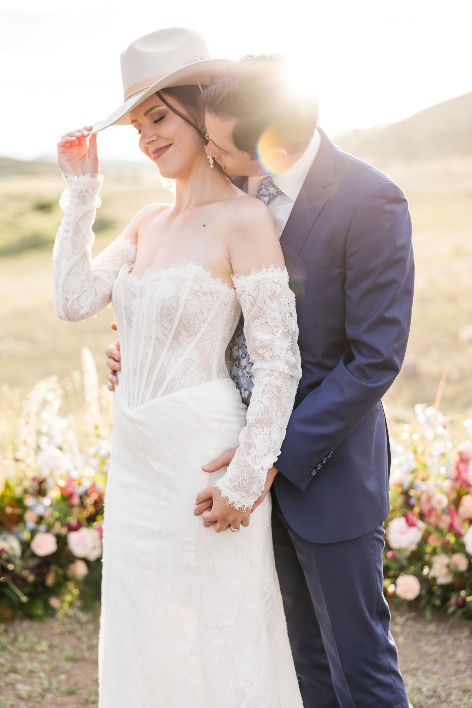 Colorado Wedding Photo with Romantic wedding couple embraces in garden with pink roses during golden hour sunset.