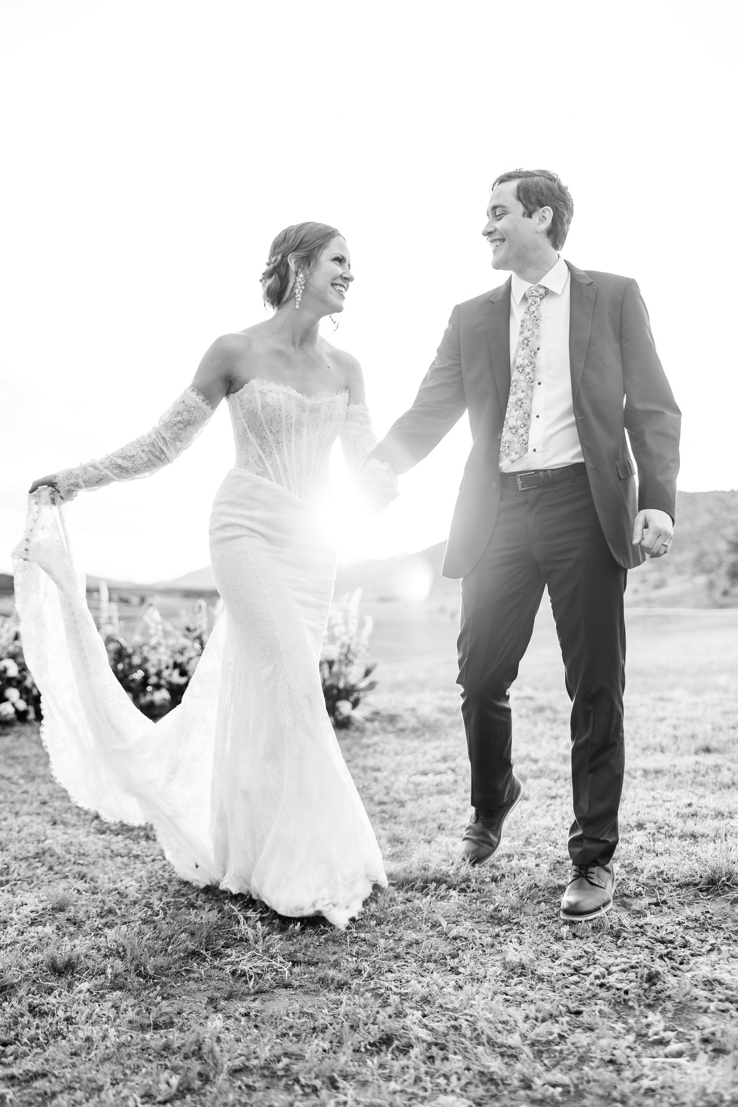 Black and white series of newlyweds running and playing in a grassy field, their joy captured in motion.
