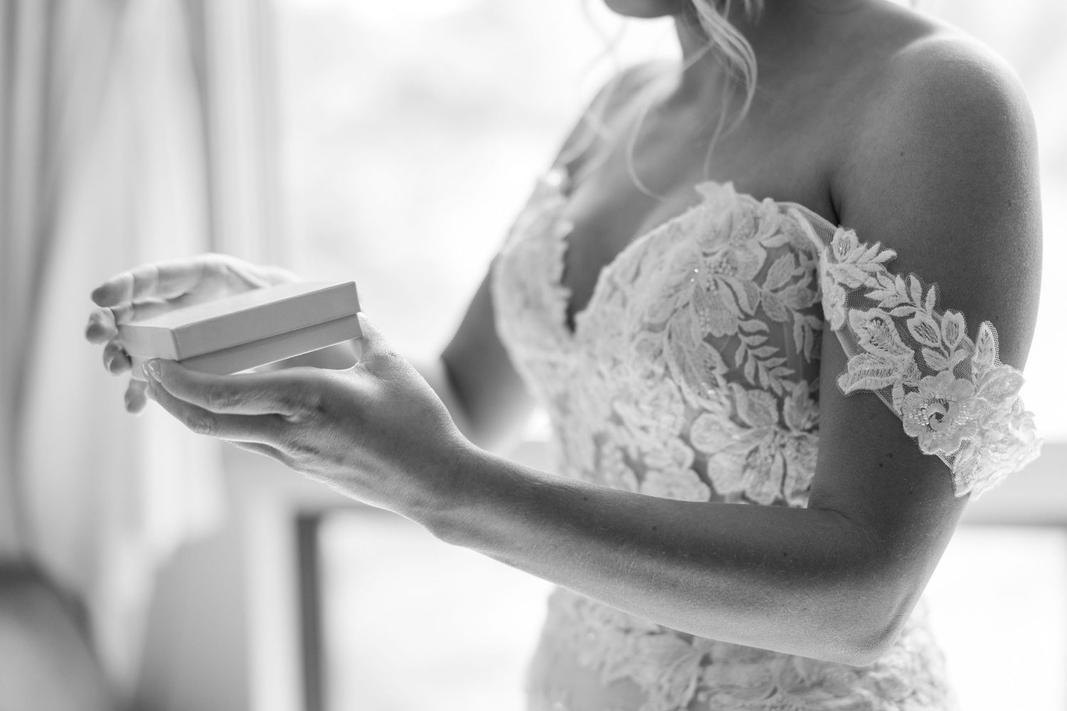 A close-up black and white photo of hands placing a wedding ring during a marriage ceremony.