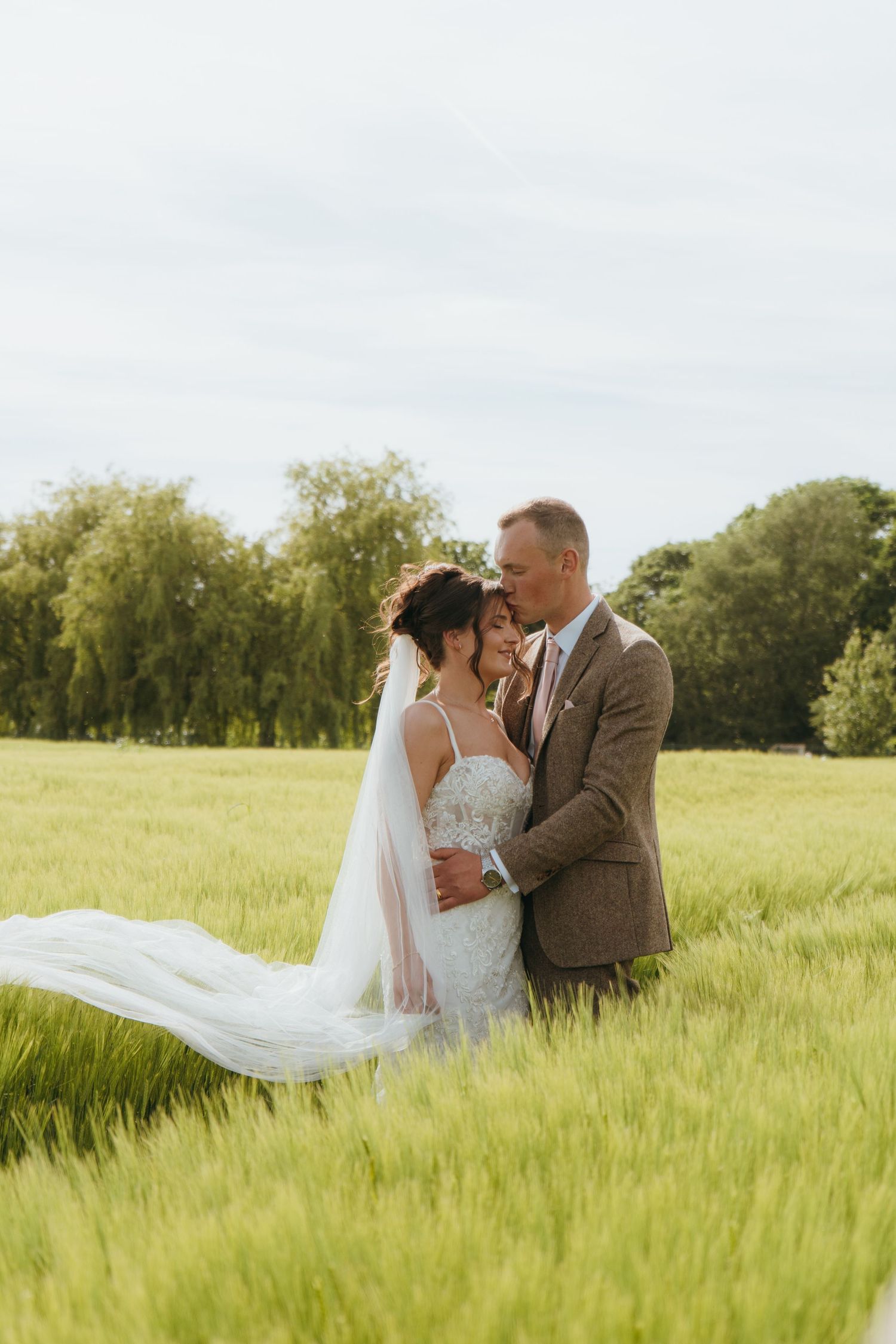 Newlyweds posing in a field of barley captured by luxury wedding content creator Unveil by Hollie