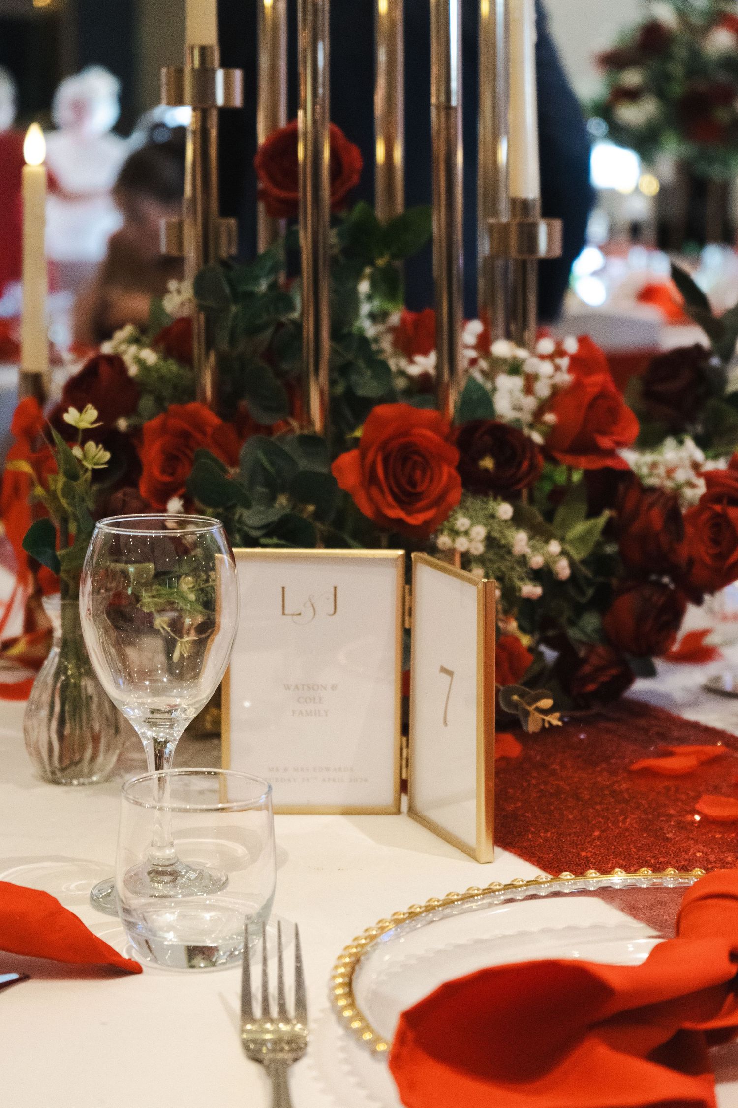 Elegant wedding reception tablescape featuring romantic red florals, candlelight and personalised place settings, captured by luxury wedding