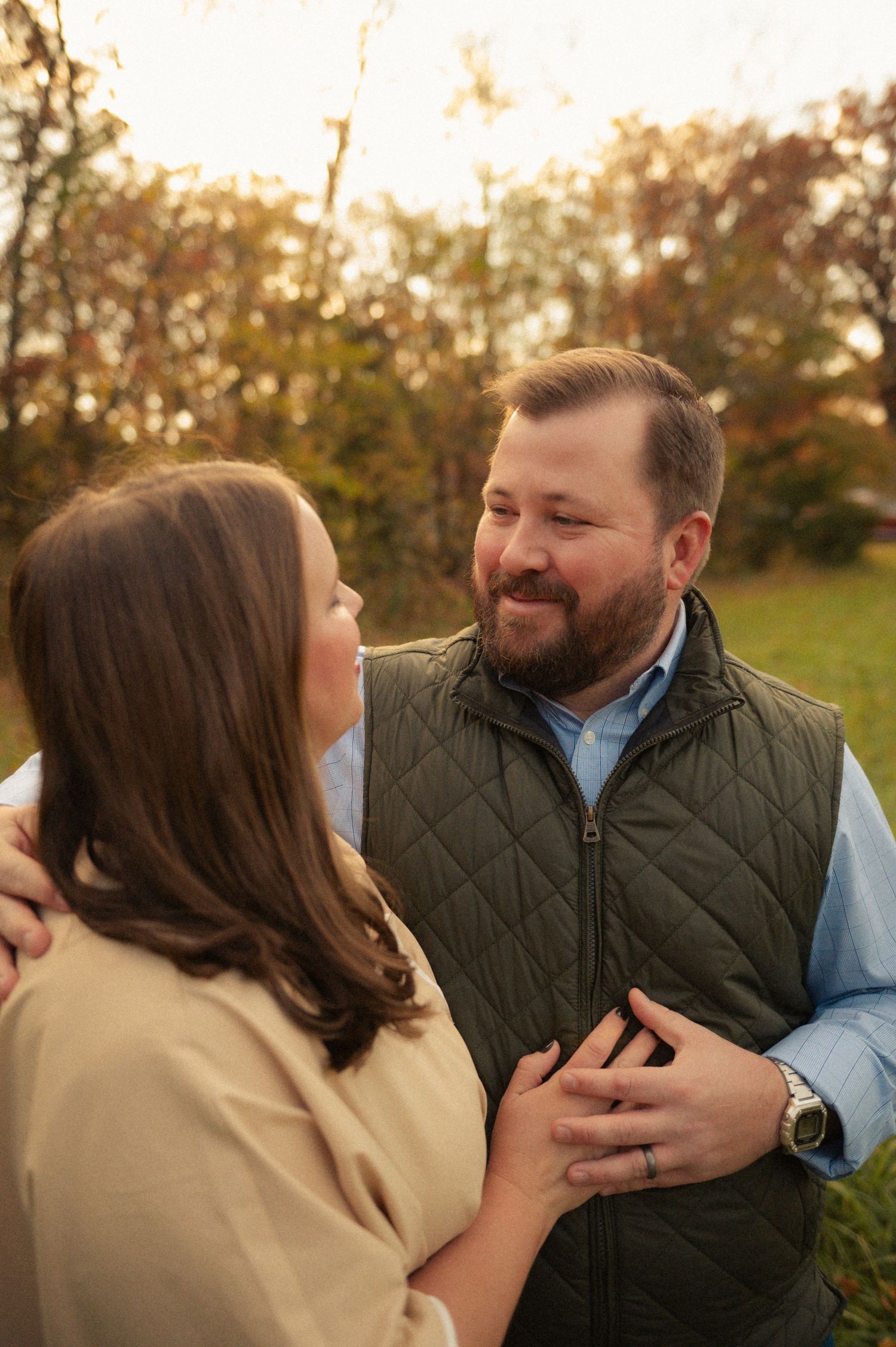 Couple sharing a tender moment outdoors in autumn, man smiling warmly at woman in golden fall light.