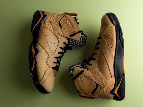 Brown and blue Air Jordan 7 retro sneakers displayed on a green background.