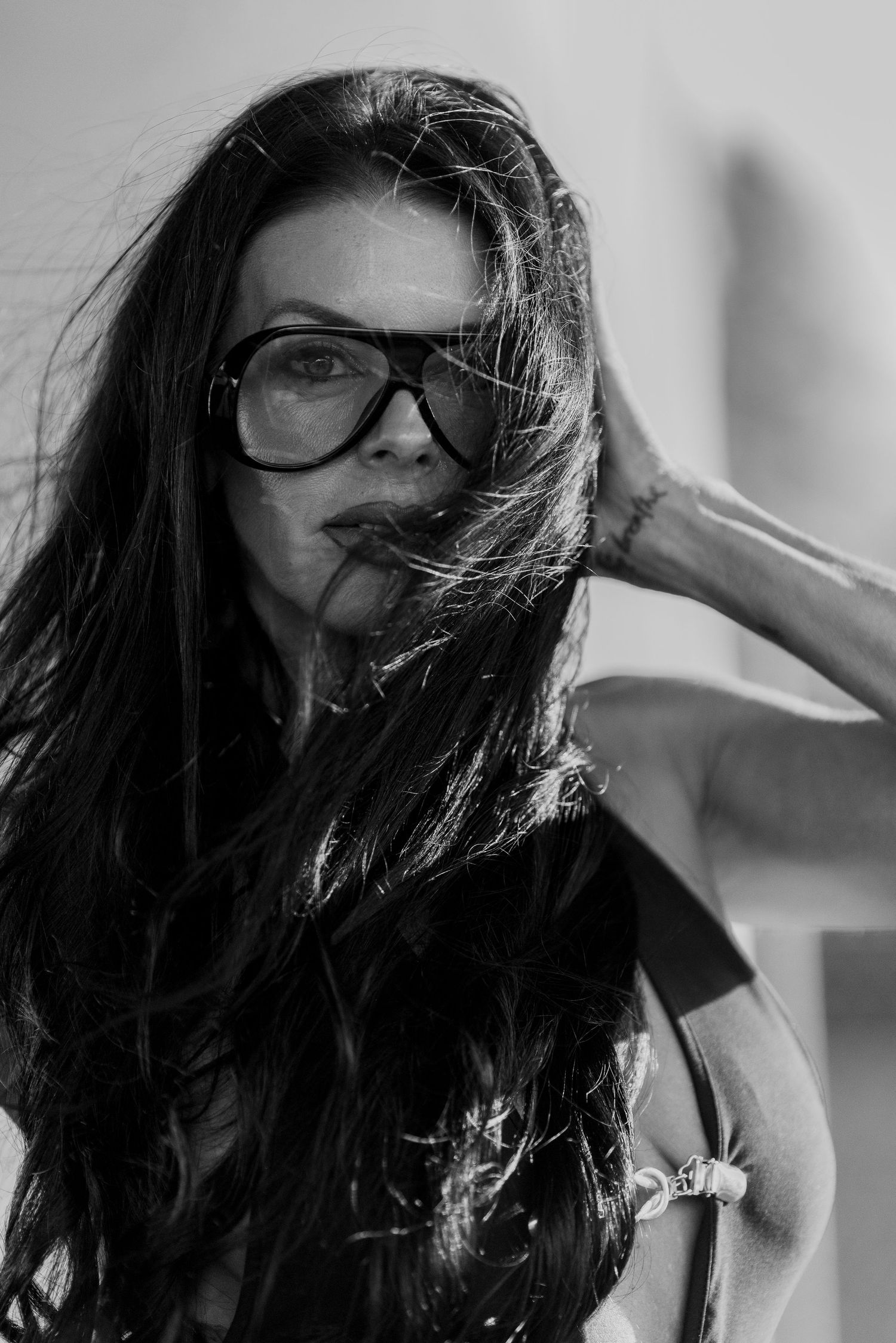 Black and white portrait of woman with long dark hair and oversized glasses.