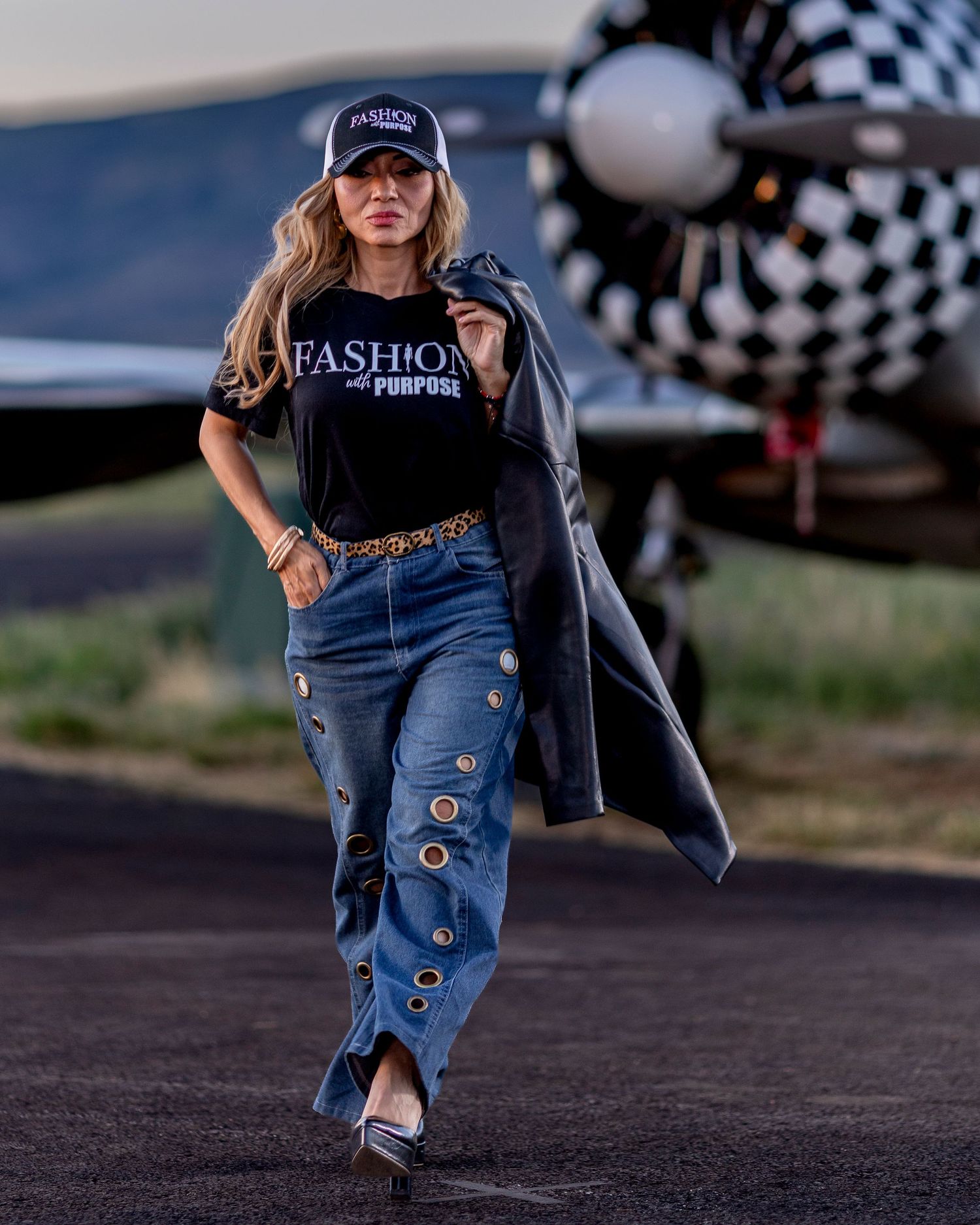 Confident woman in Fashion with Purpose tee and jeans walking on airport tarmac.