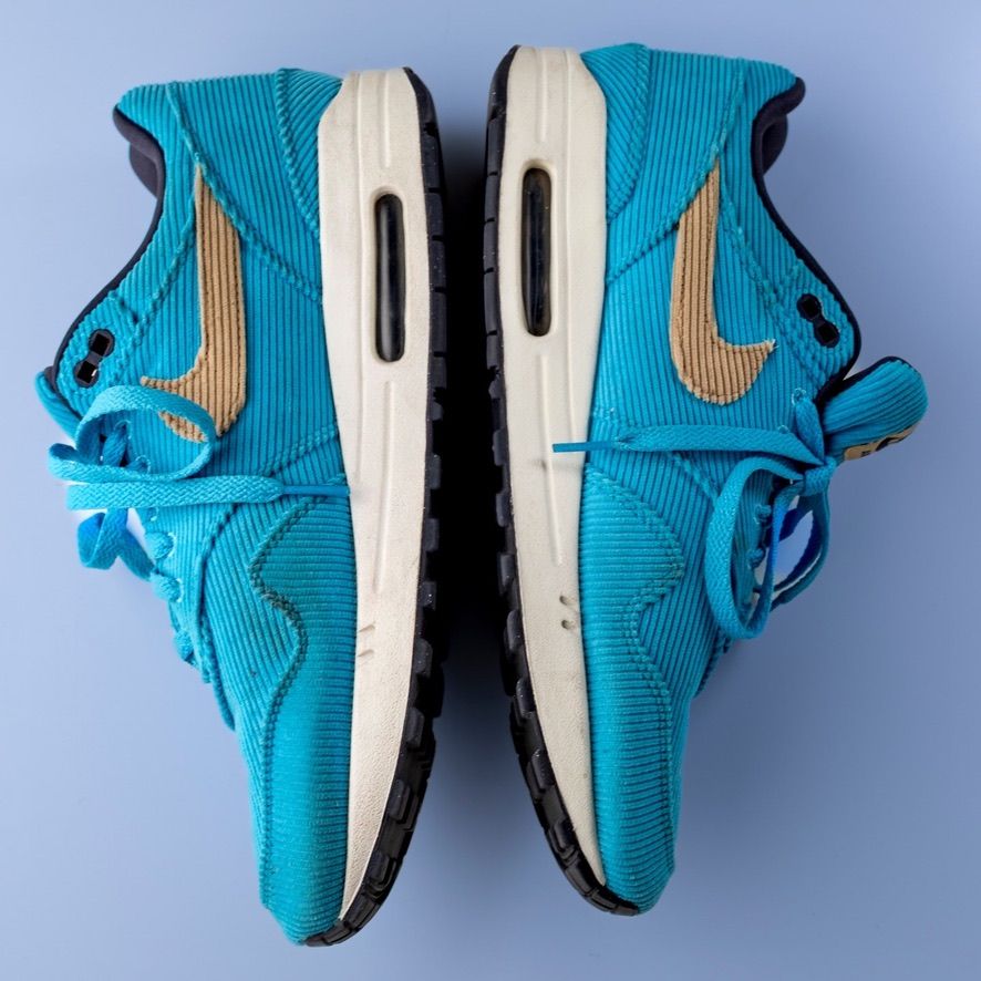 Pair of teal blue Nike Air Max sneakers with gold swoosh and white midsole viewed from above.