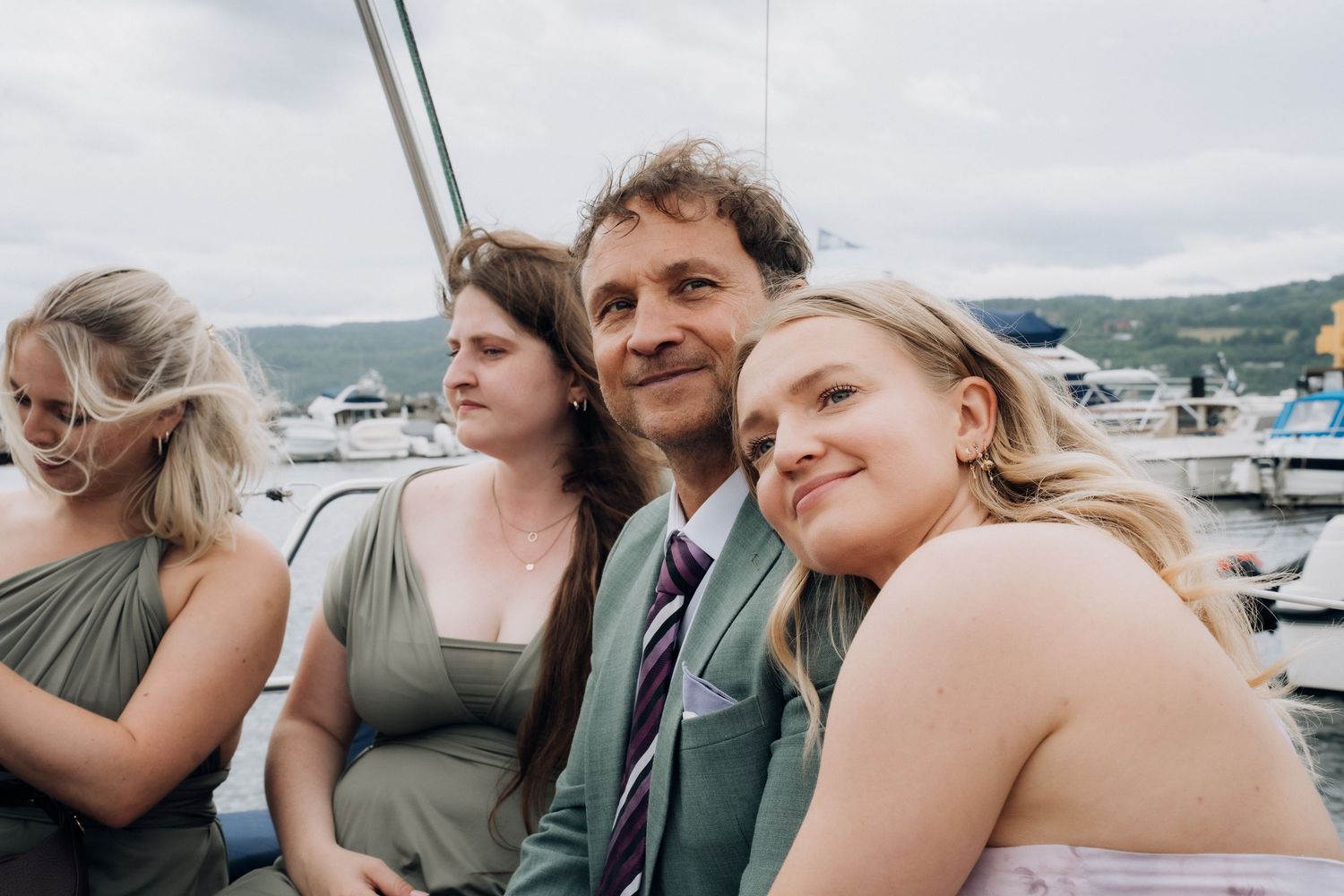 Wedding guests smiling together on a sailboat at a marina during a reception.
