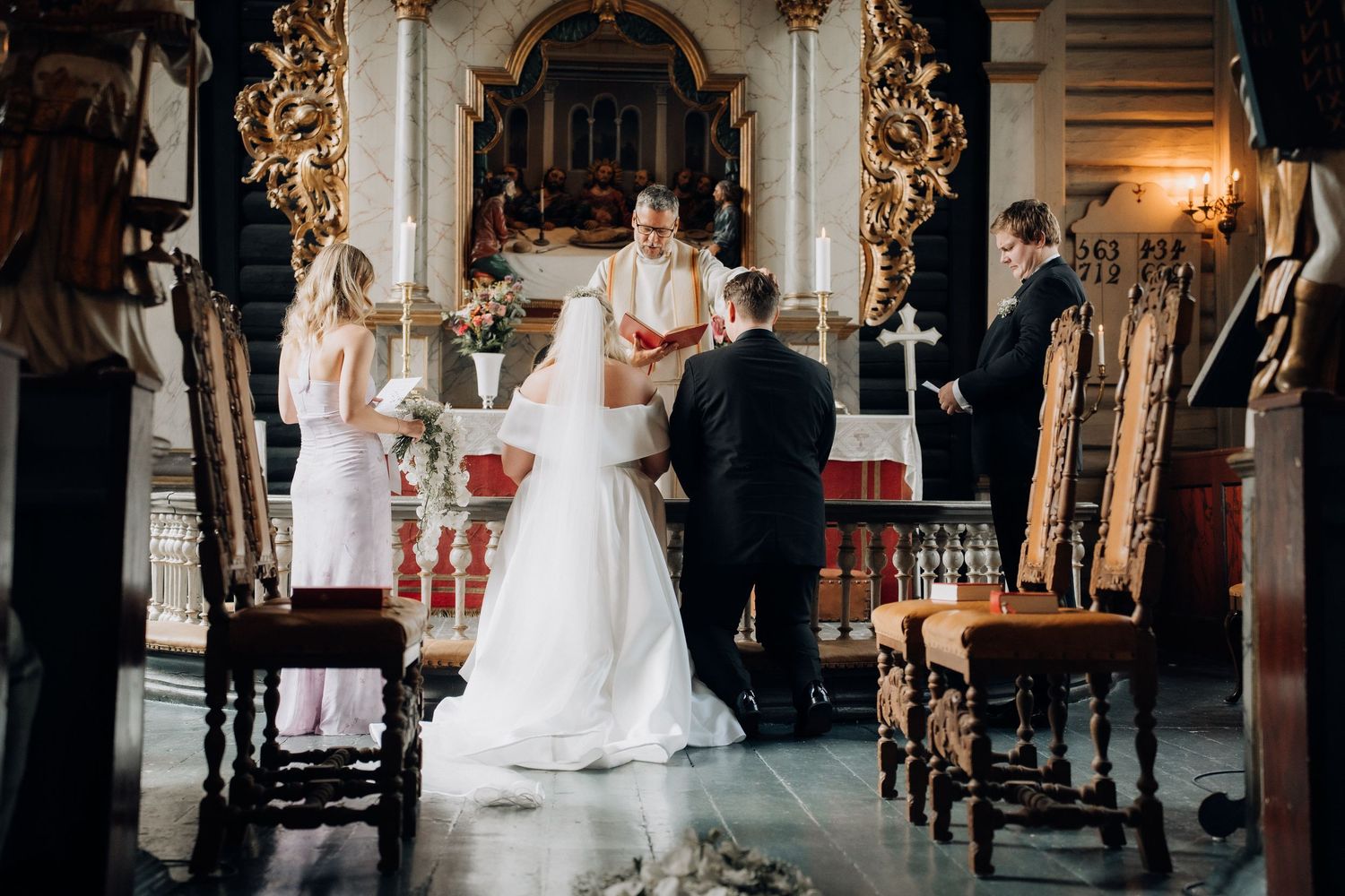 Bride and groom exchange vows at ornate church altar with officiant during traditional wedding ceremony.