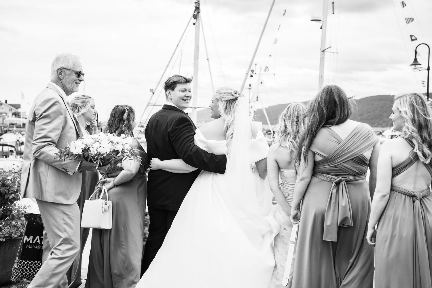Bride and groom sharing first kiss at outdoor marina wedding ceremony with guests.