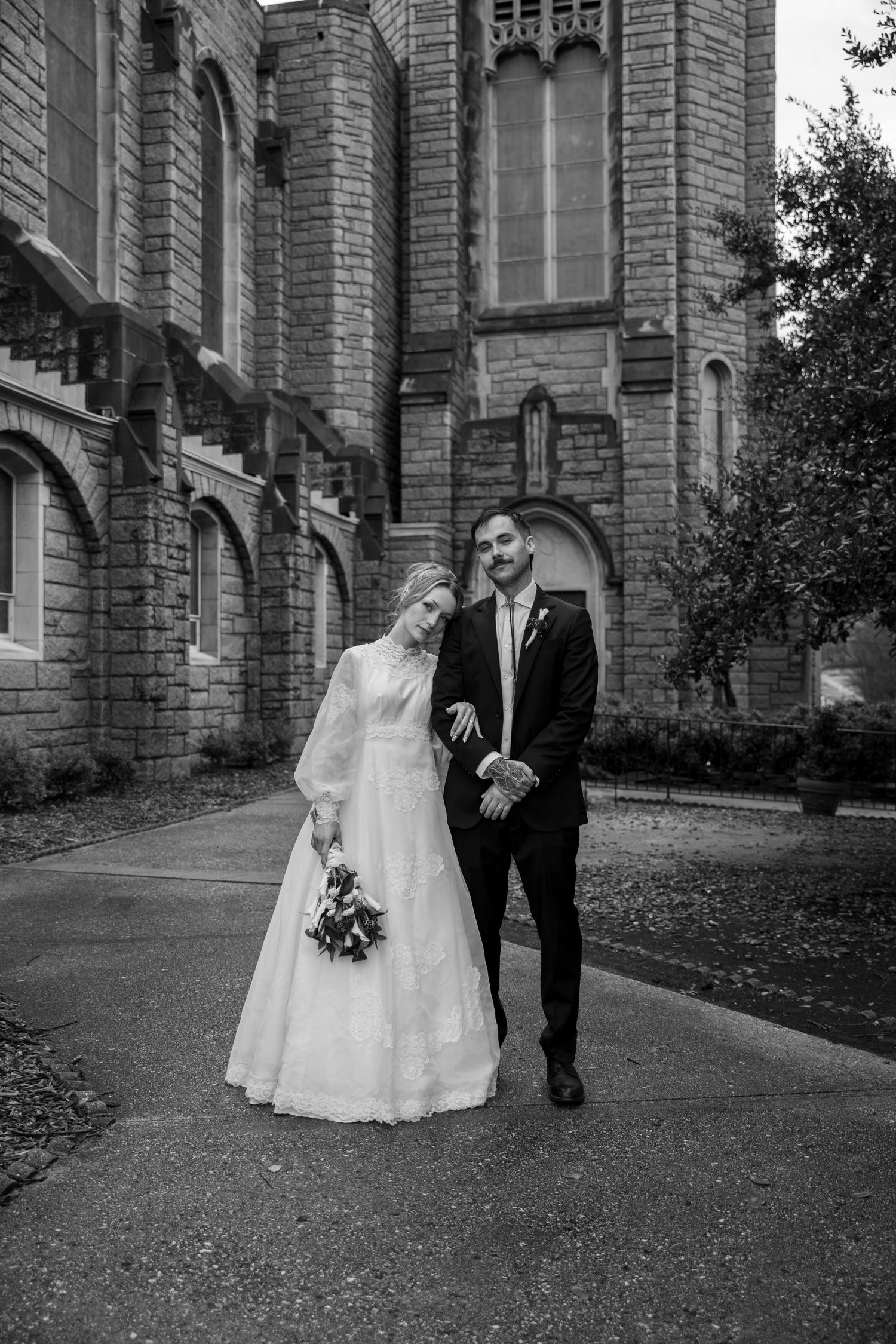 Black and white photo of newlyweds walking outside a Gothic church