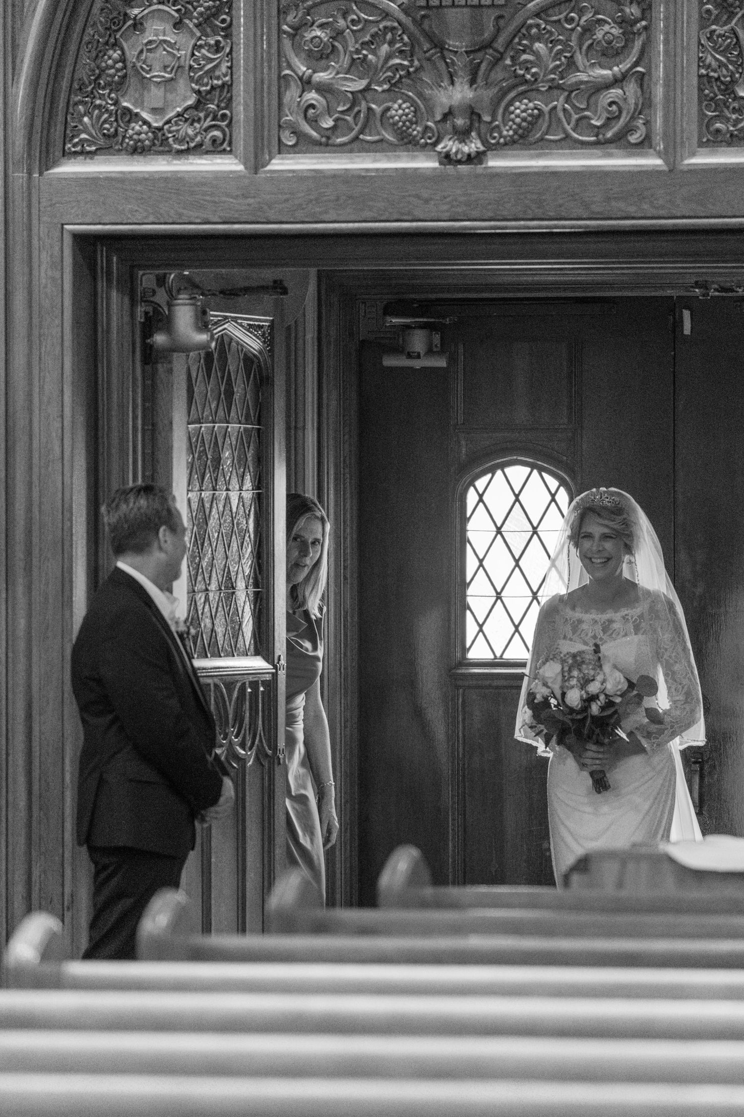 Black and white photo of the bride waiting at the church doors with her father
