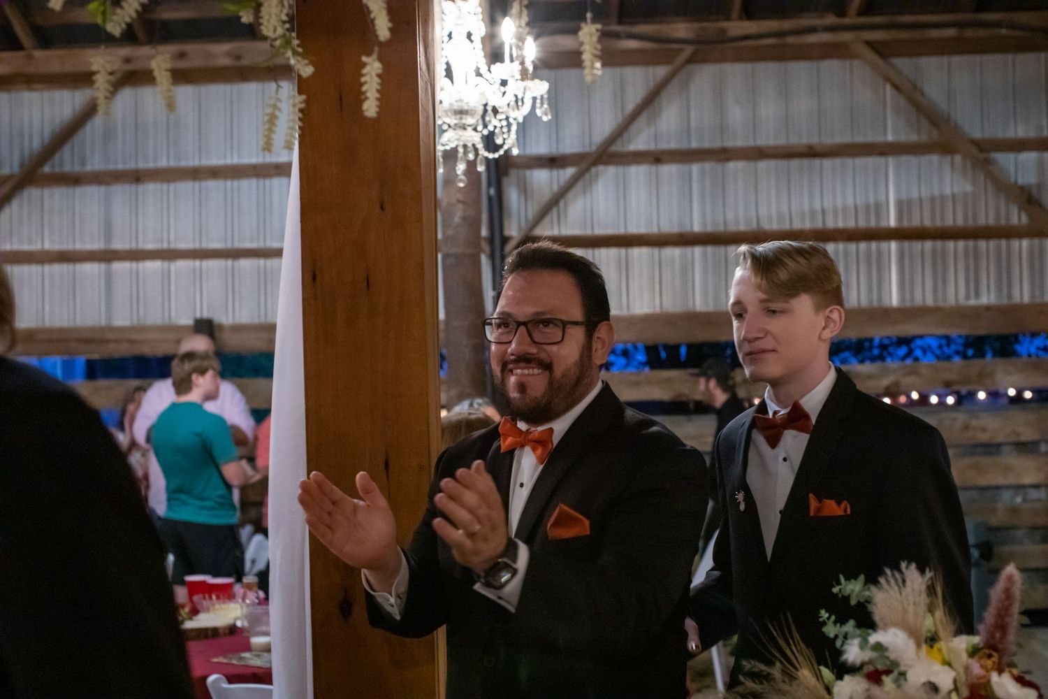 Groomsmen applauding the newlyweds at a barn wedding reception
