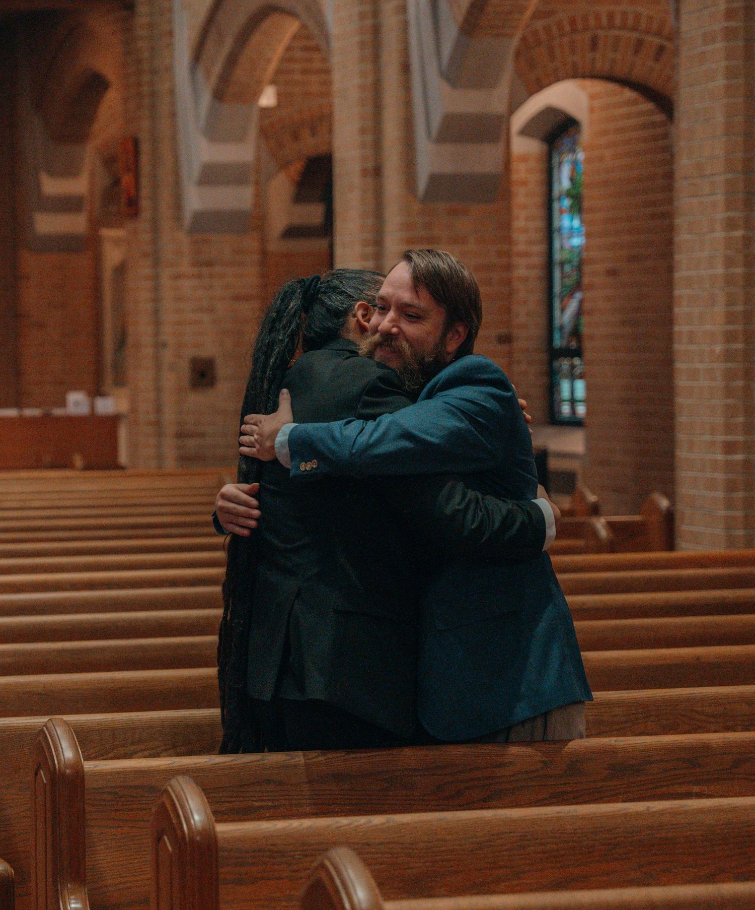 Bride hugging a guest in the pews of a Catholic church