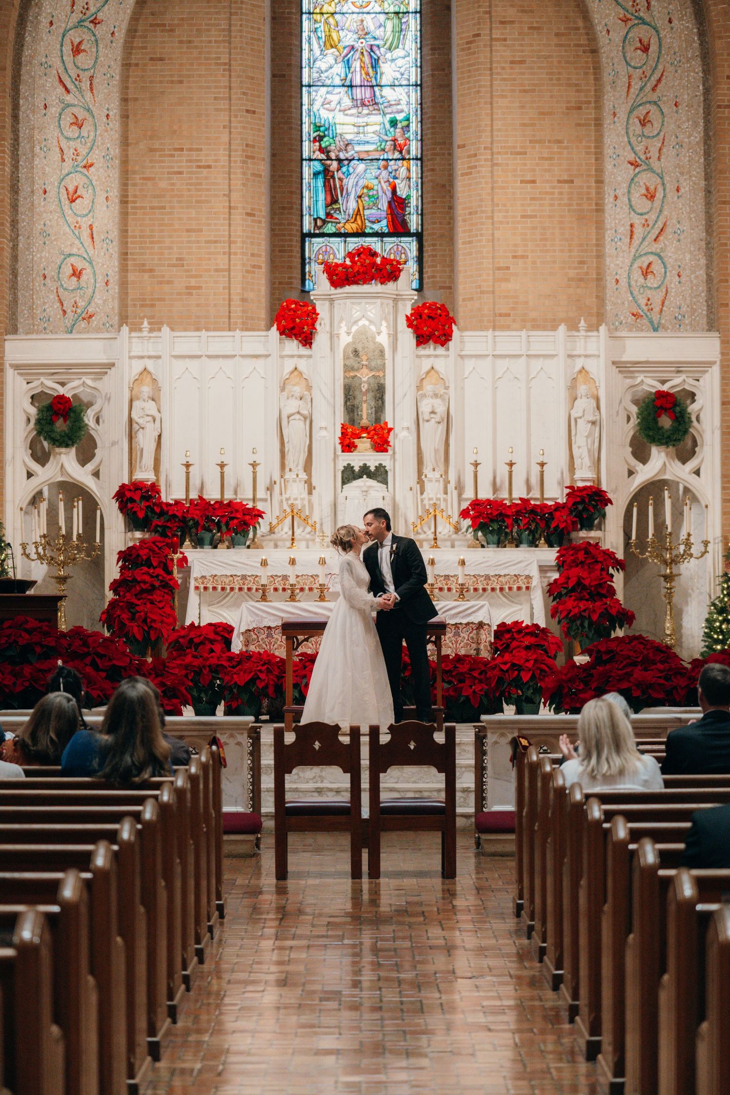 Wide view of a Catholic church altar decorated with red poinsettias for a wedding