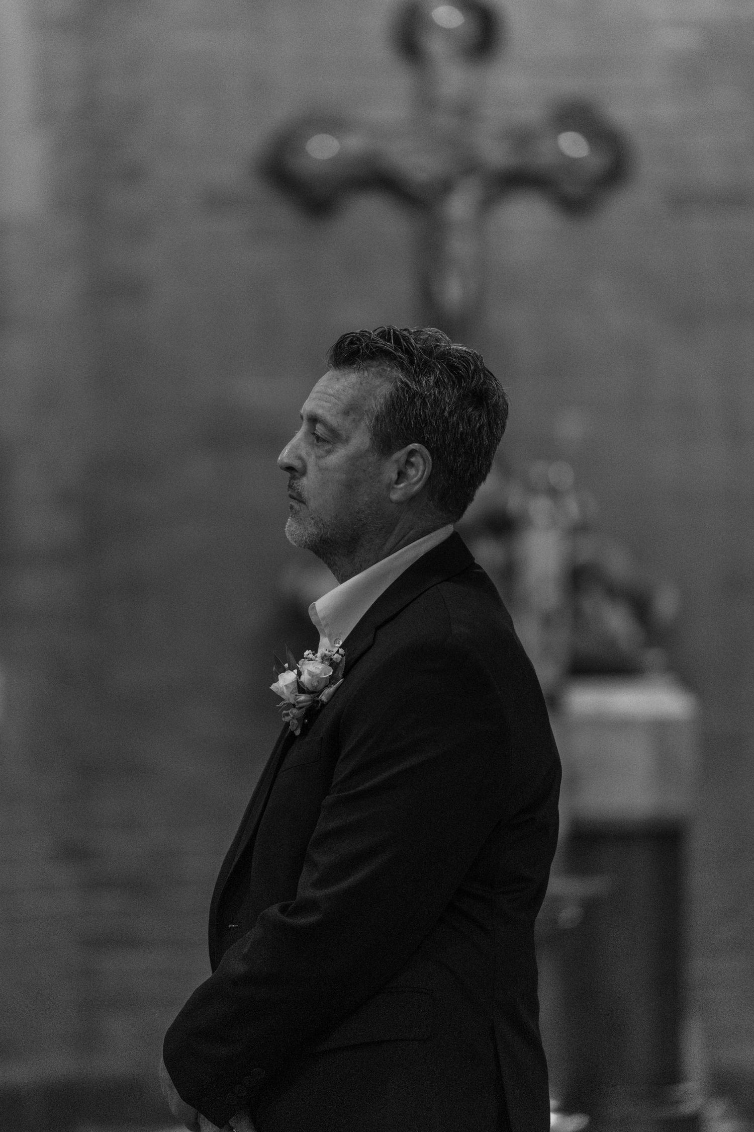 Black and white portrait of the groom in quiet prayer before his wedding