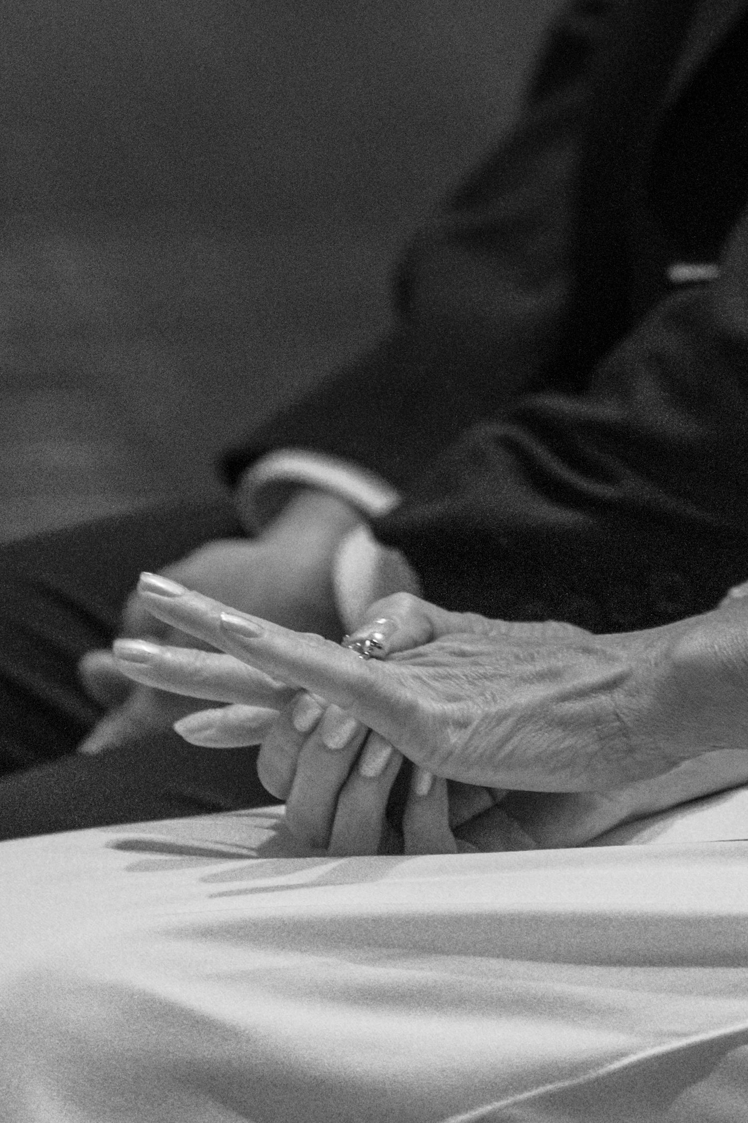 Black and white close-up of the bride and groom holding hands during Mass