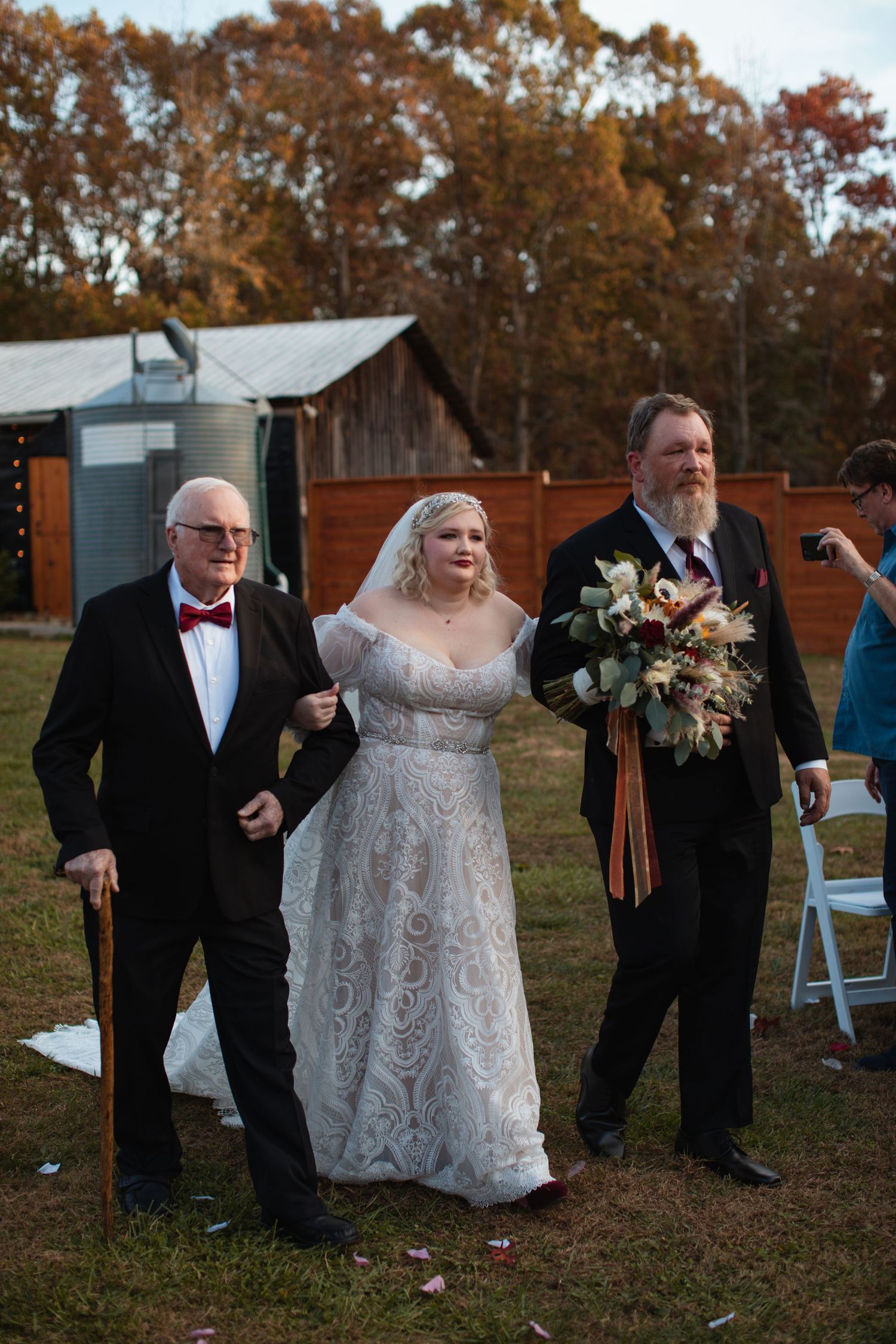 Bride walking down the aisle between two family members at an outdoor ceremony
