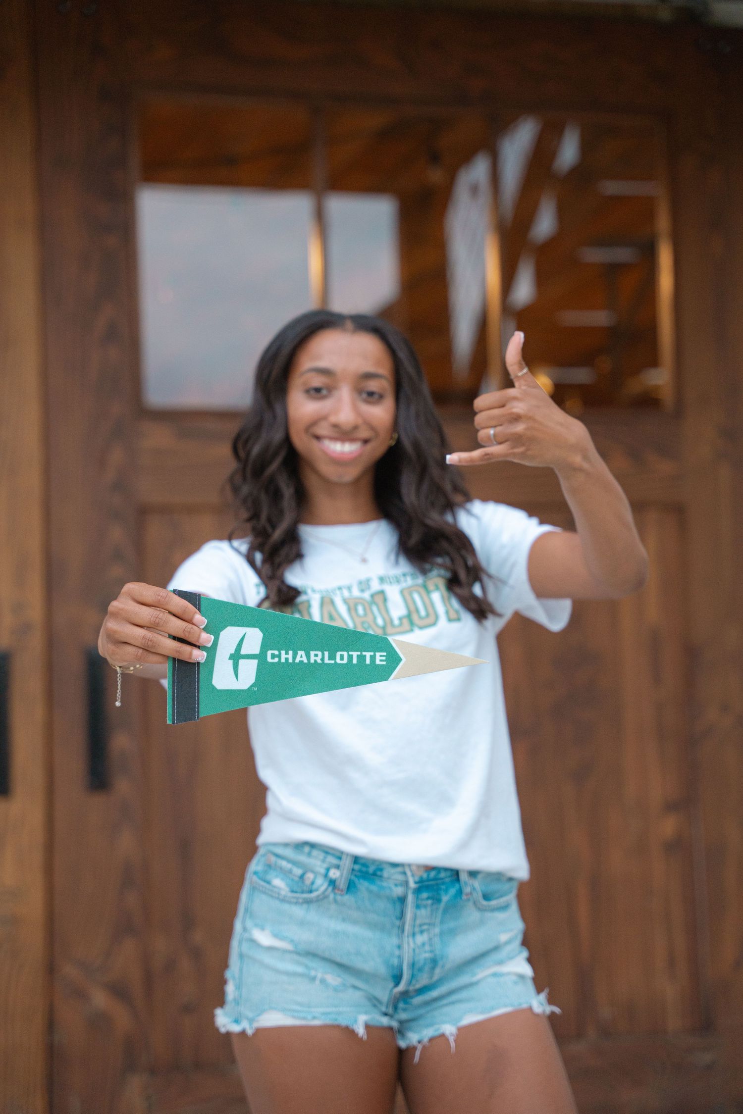 Graduate holding a UNC Charlotte pennant and giving a thumbs up for her college decision photo