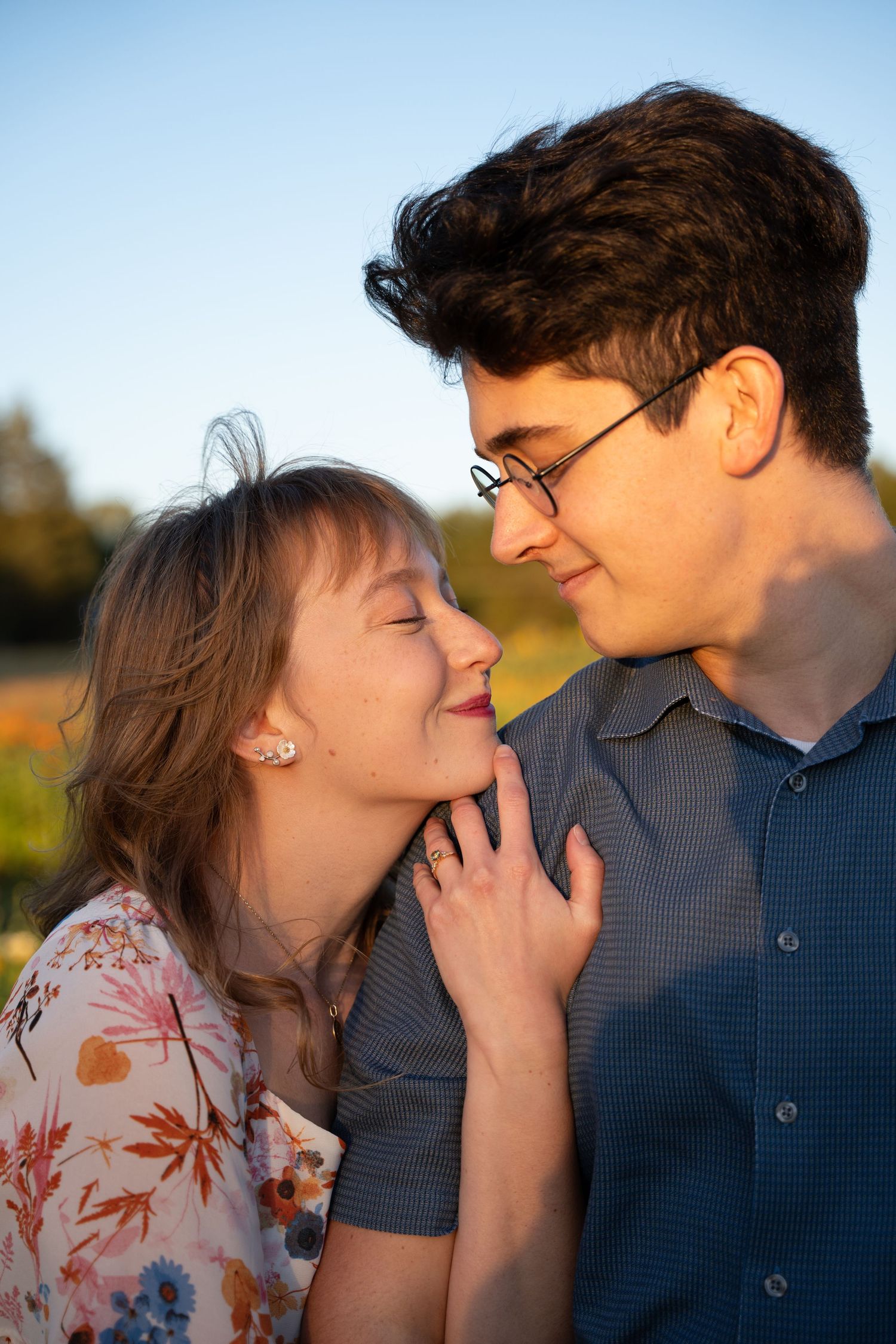 Engaged couple cuddling and smiling in golden evening light