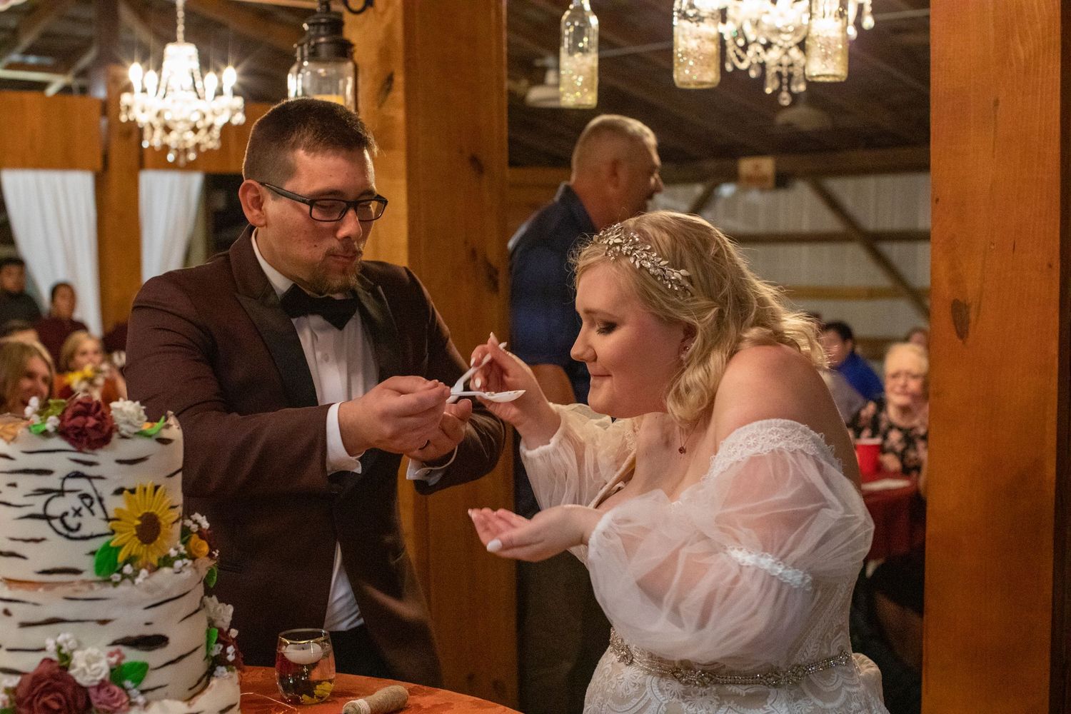 Newlyweds cutting a floral wedding cake in a rustic barn venue