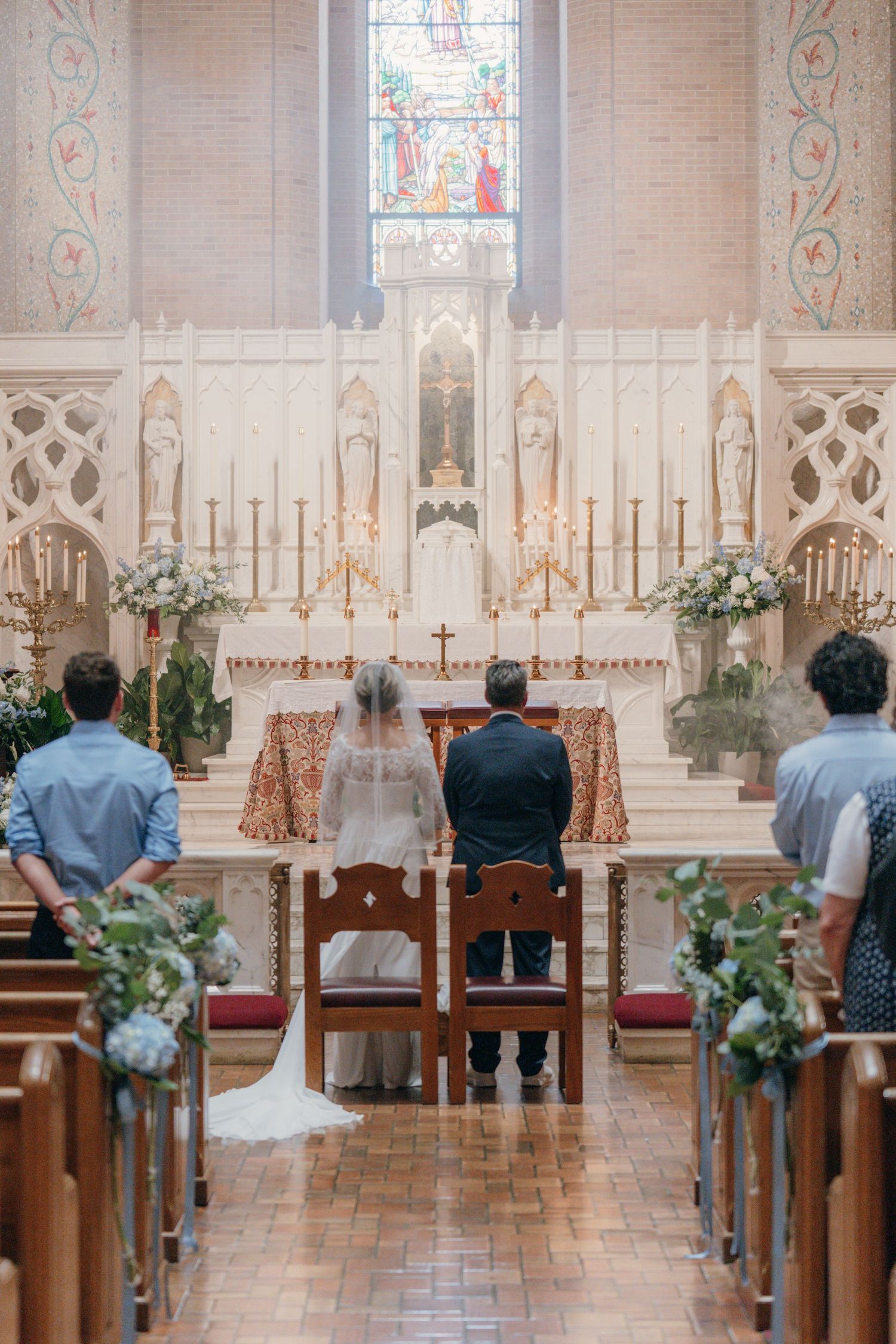 Bride and groom at the altar of a church with blue and white floral pew decor