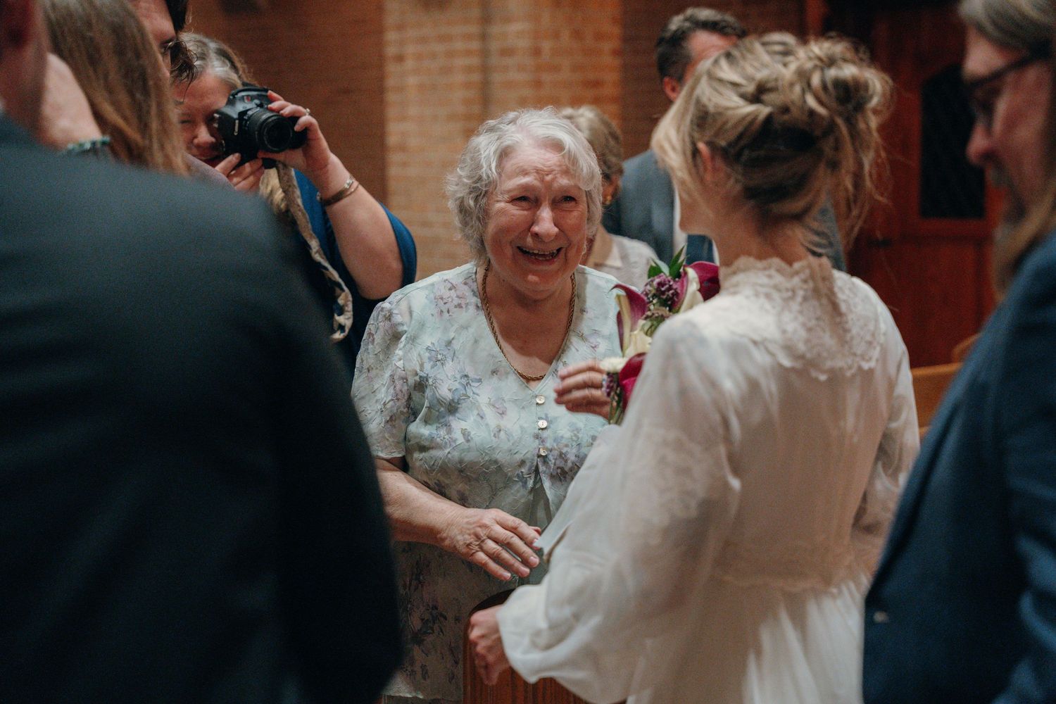Smiling grandmother greeting the bride after the wedding ceremony