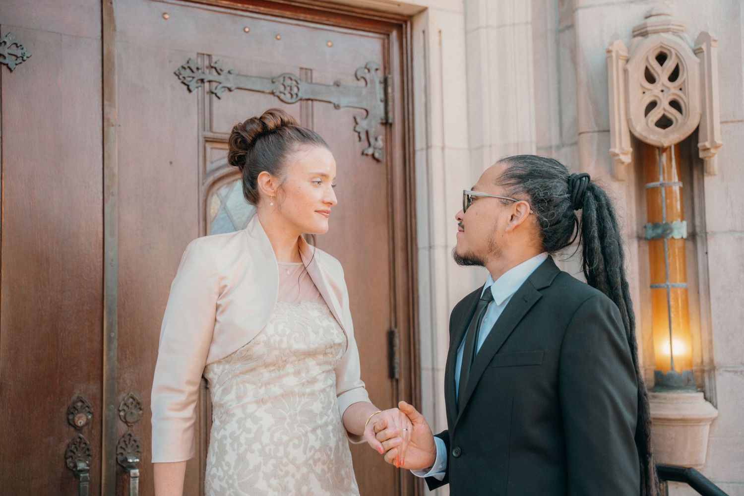 Bride and groom holding hands at the carved wooden doors of a church