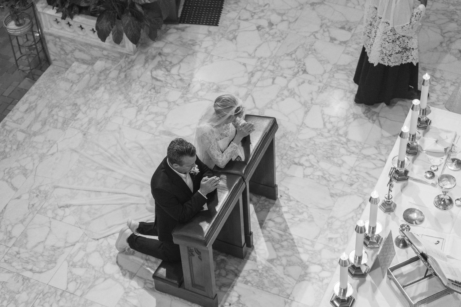 Black and white overhead view of the bride and groom kneeling at the altar