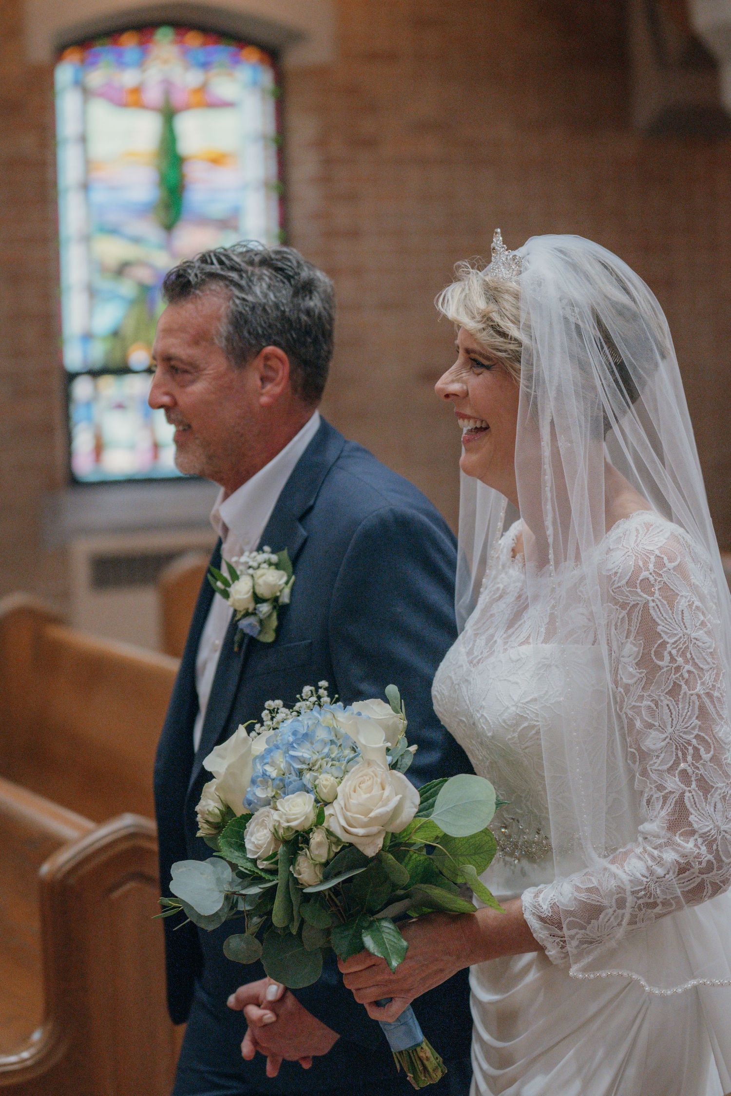 Father of the bride smiling as he walks his daughter down the aisle
