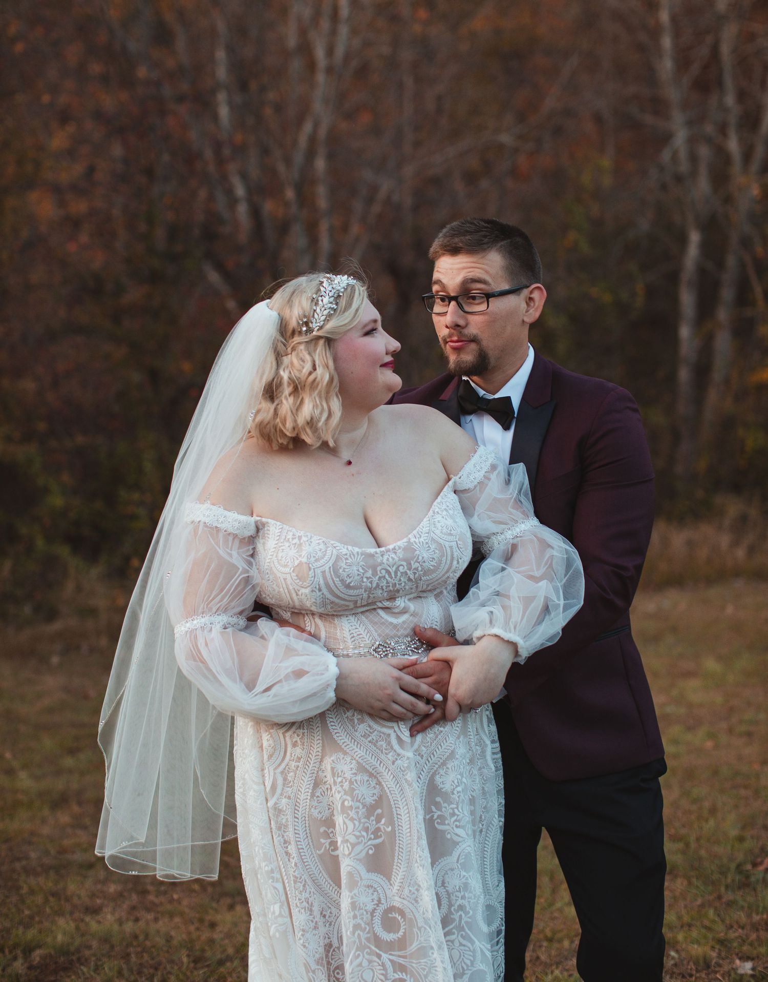 Bride and groom embracing in front of autumn trees