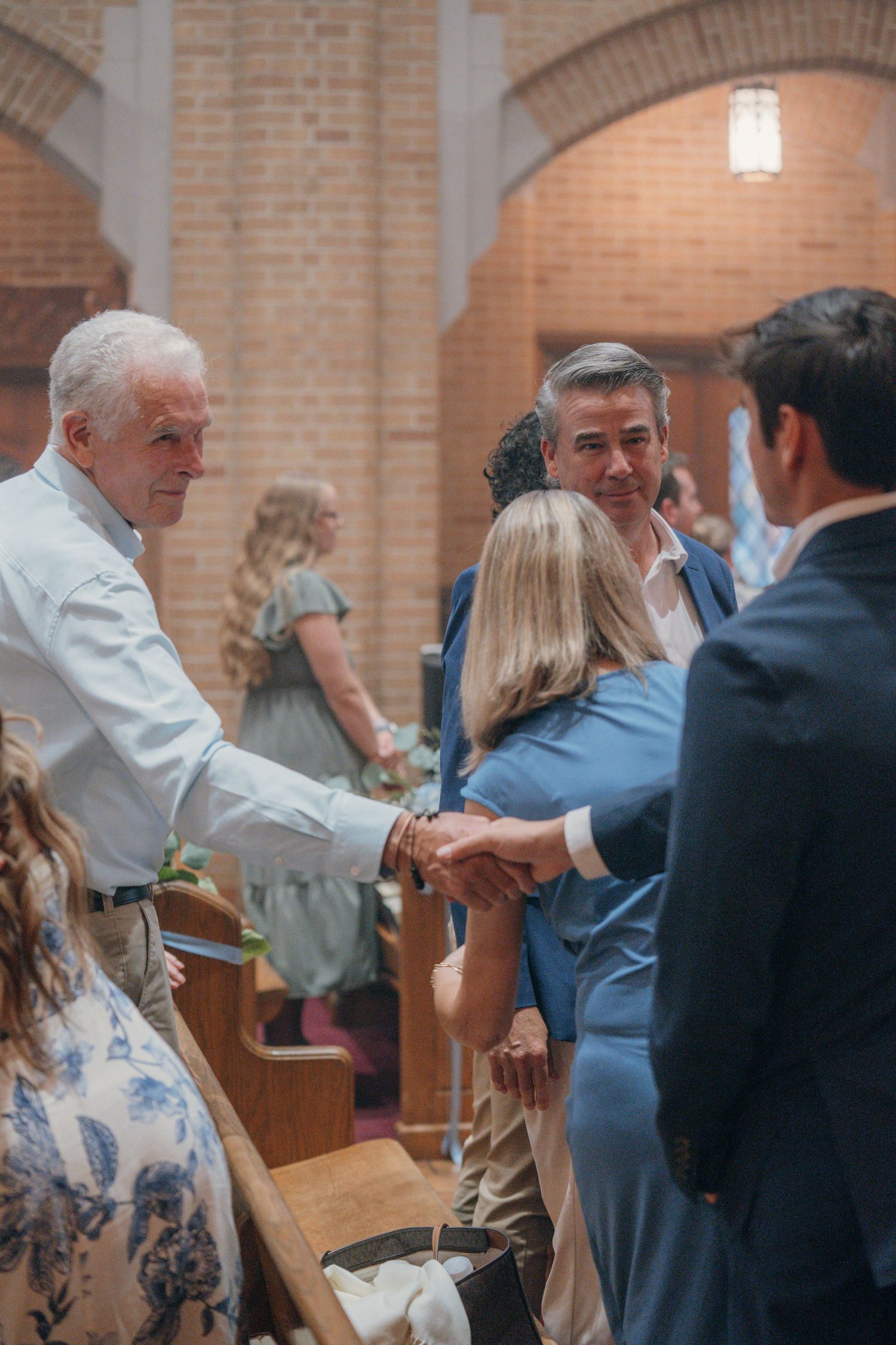 Guests shaking hands during the sign of peace at a Catholic wedding