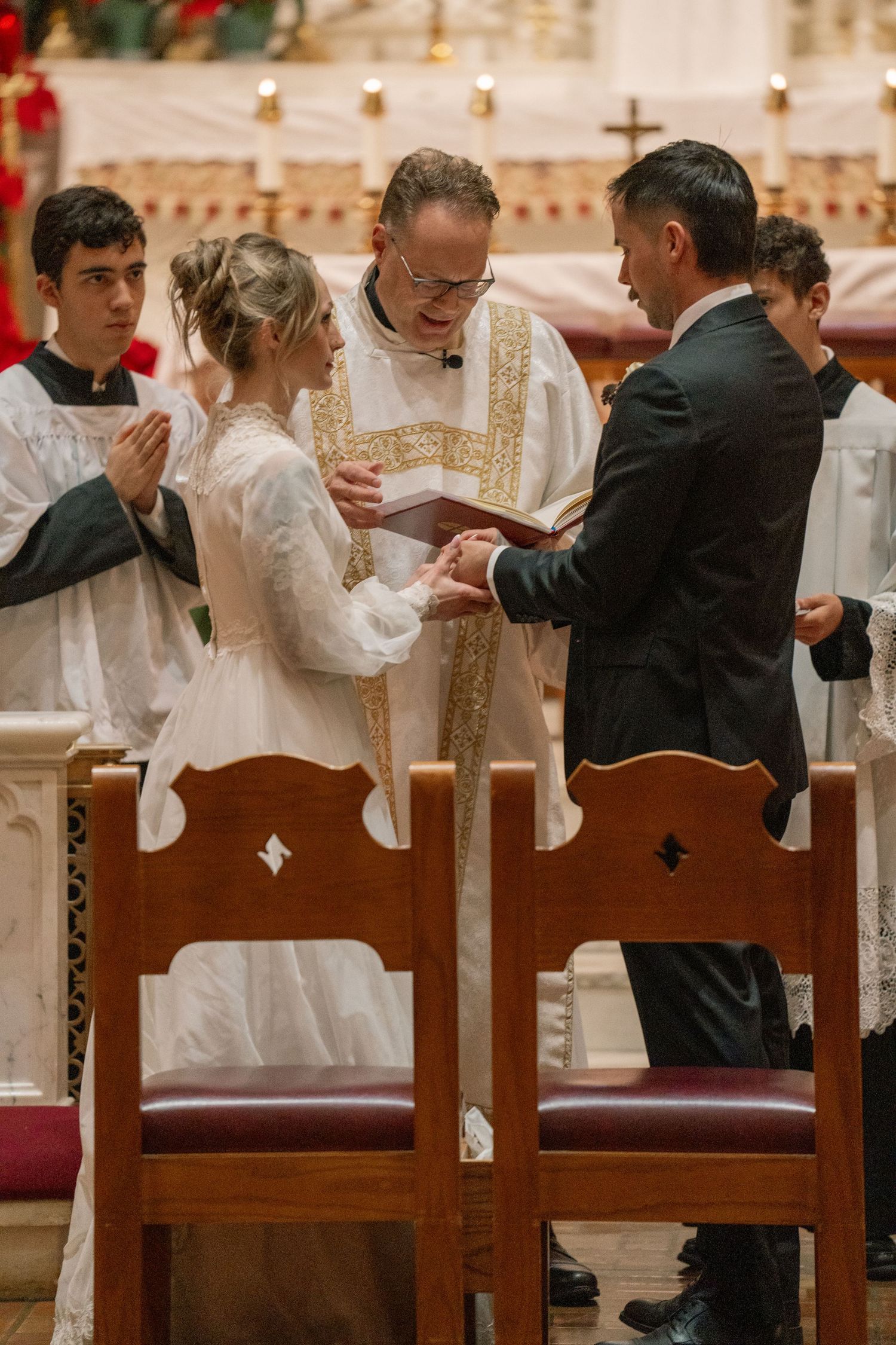 Priest blessing the rings as the bride and groom exchange vows