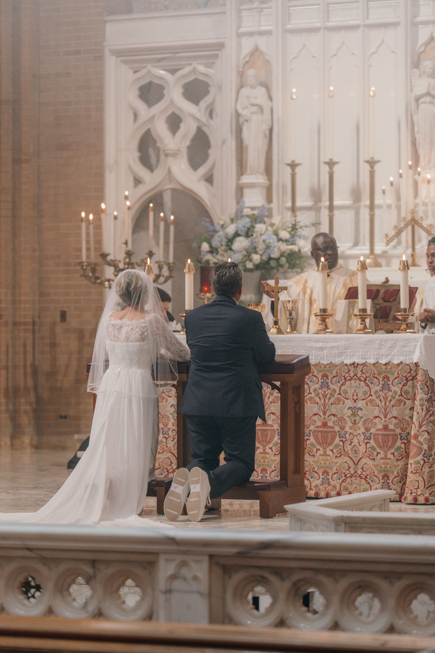 Bride and groom kneeling at prie-dieux before the altar