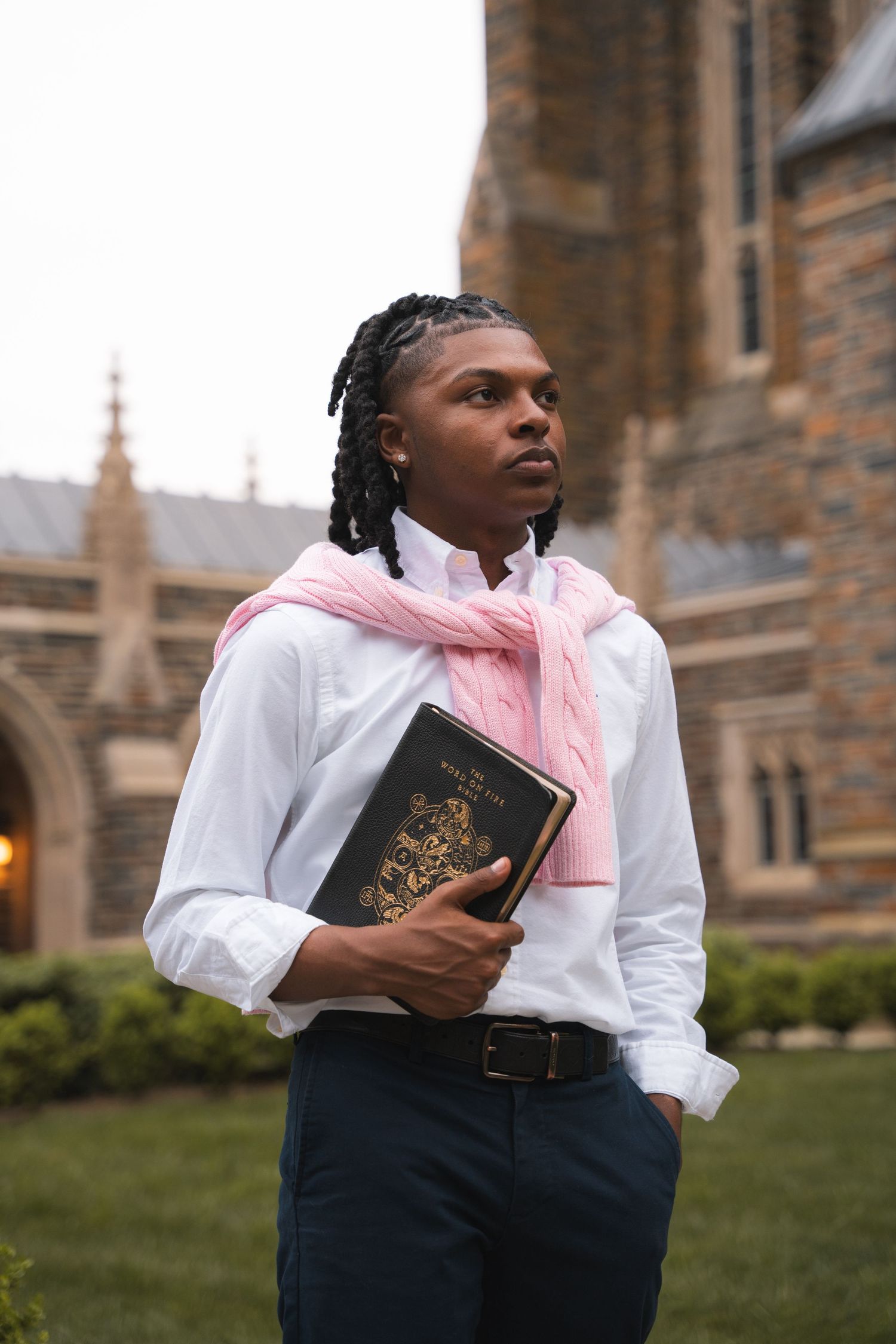 Senior portrait of a young man holding a Bible outside a stone Gothic chapel
