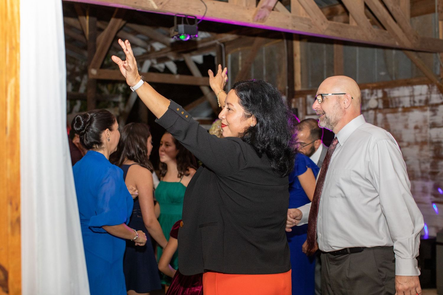 Wedding guests raising their hands on the dance floor at a barn reception