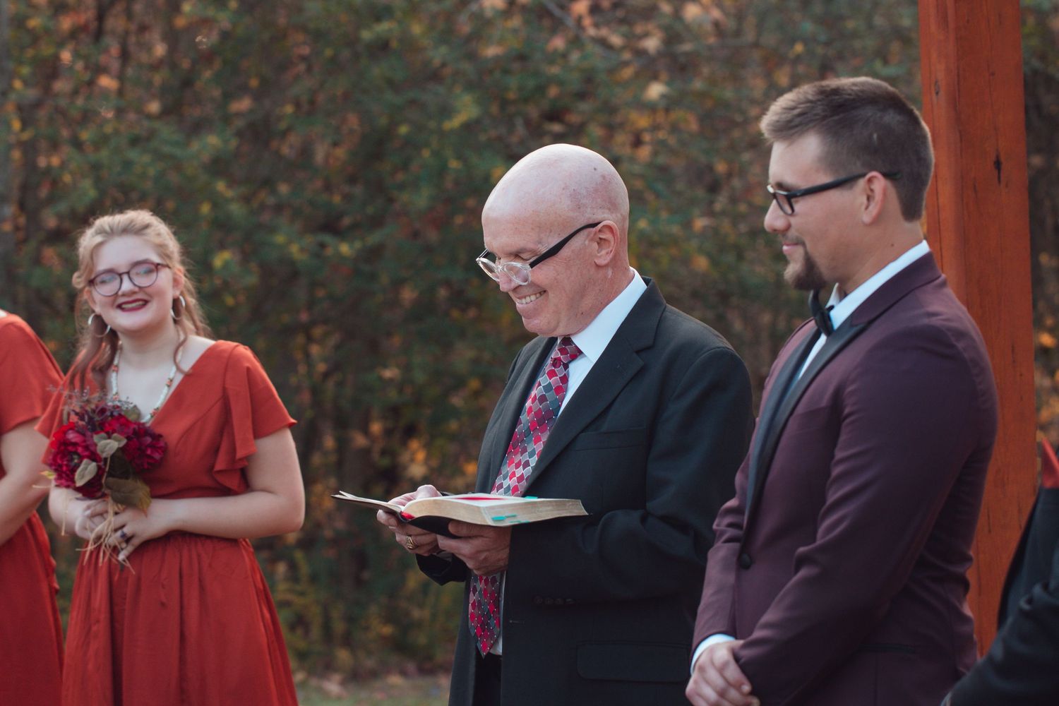 Officiant reading during an outdoor wedding ceremony as the groom and bridesmaid look on