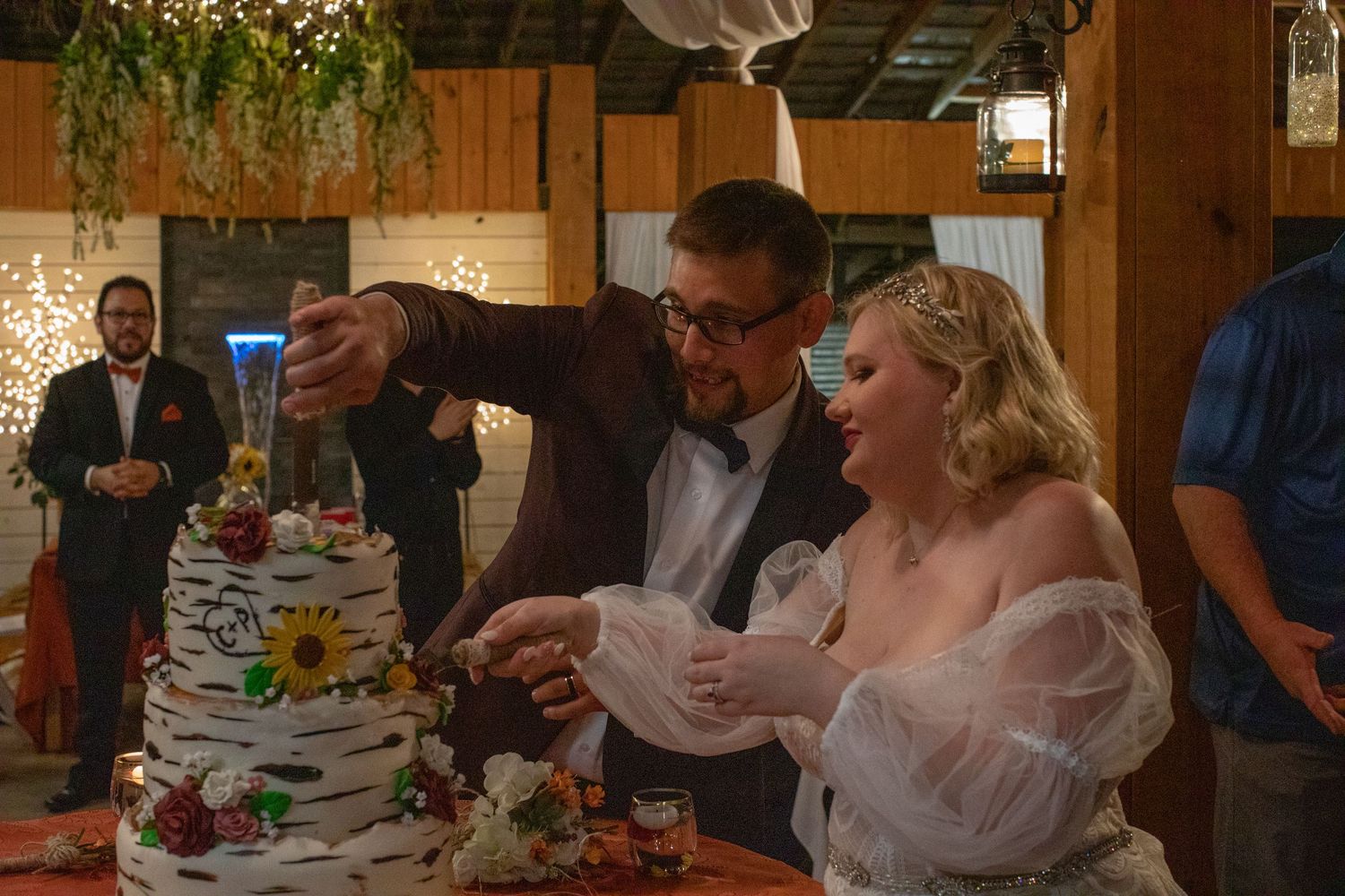 Bride and groom sharing their first bite of wedding cake at a barn reception