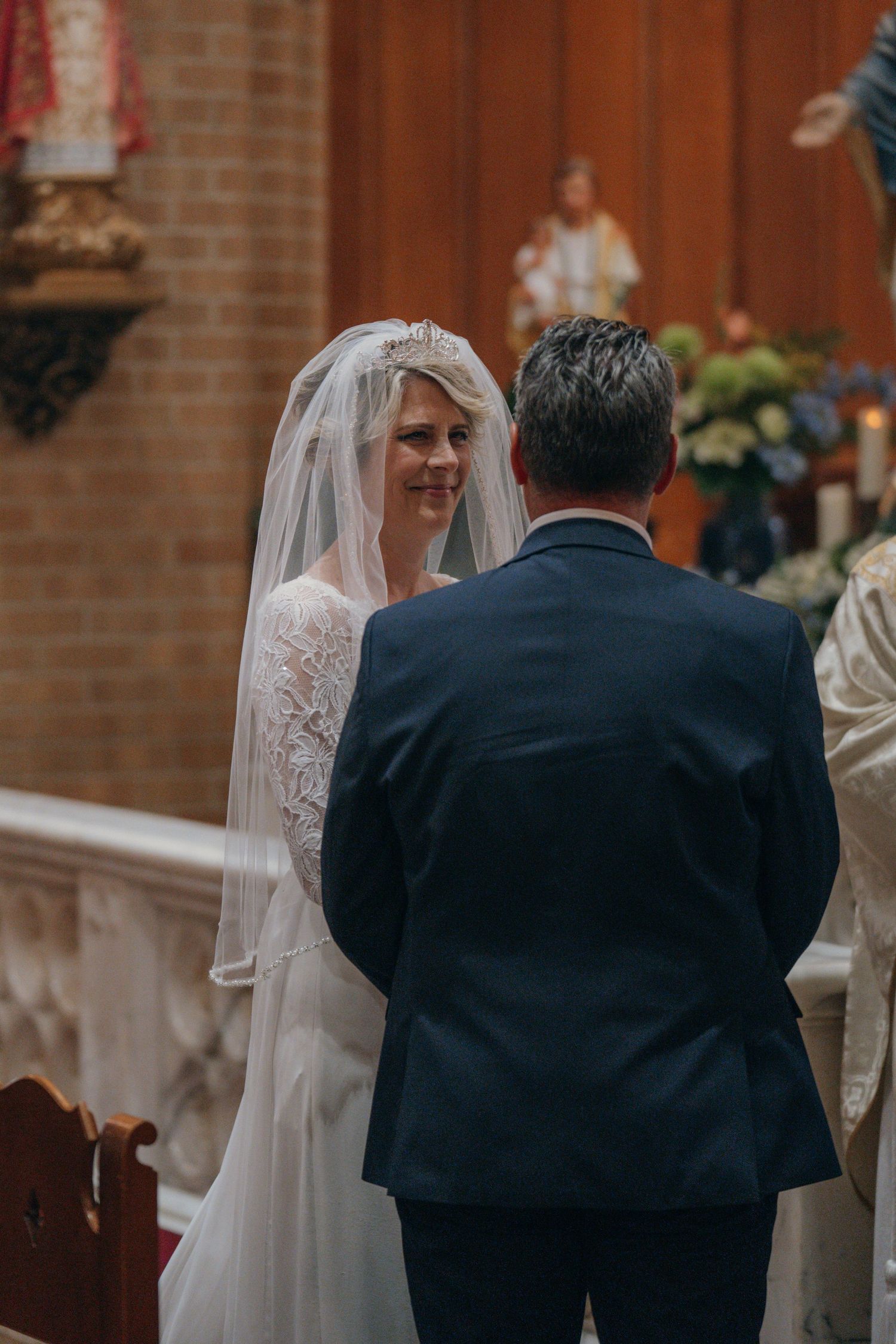 Bride in a lace veil standing beside the groom at the altar