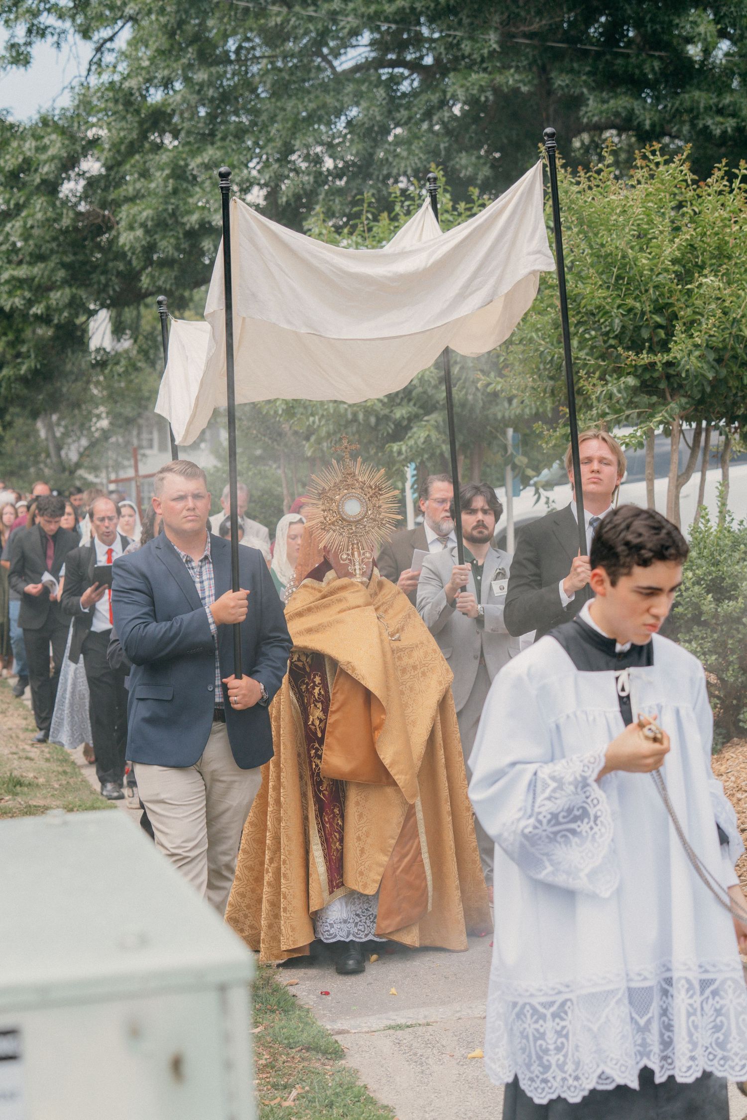 Altar server leading the priest and canopy through a Corpus Christi Eucharistic procession