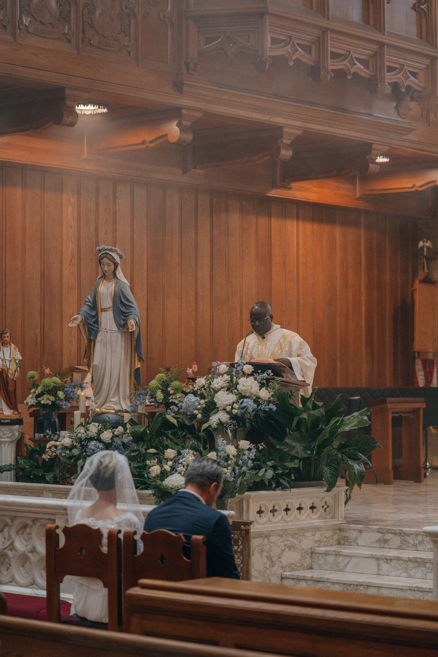 Marian altar decorated with white flowers beside the sanctuary of a Catholic church