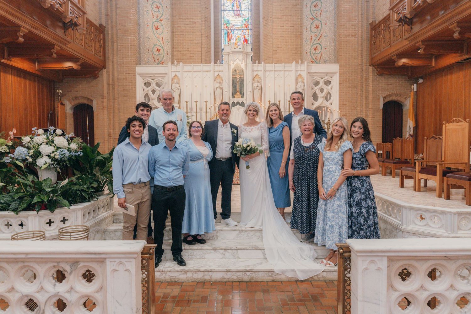 Wedding party in dusty blue posing at the altar of a Catholic church
