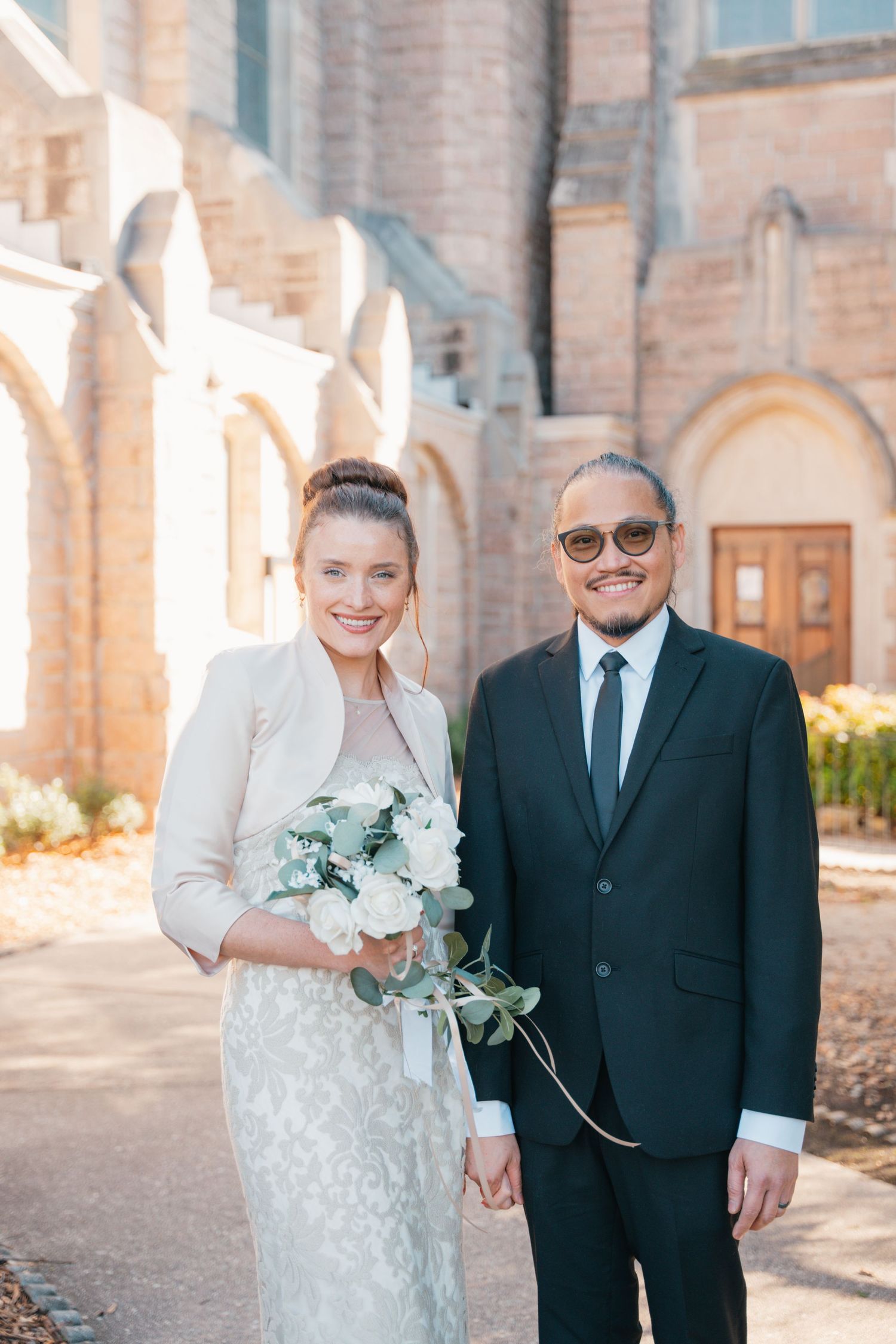 Bride and groom standing arm in arm in front of the church after their ceremony