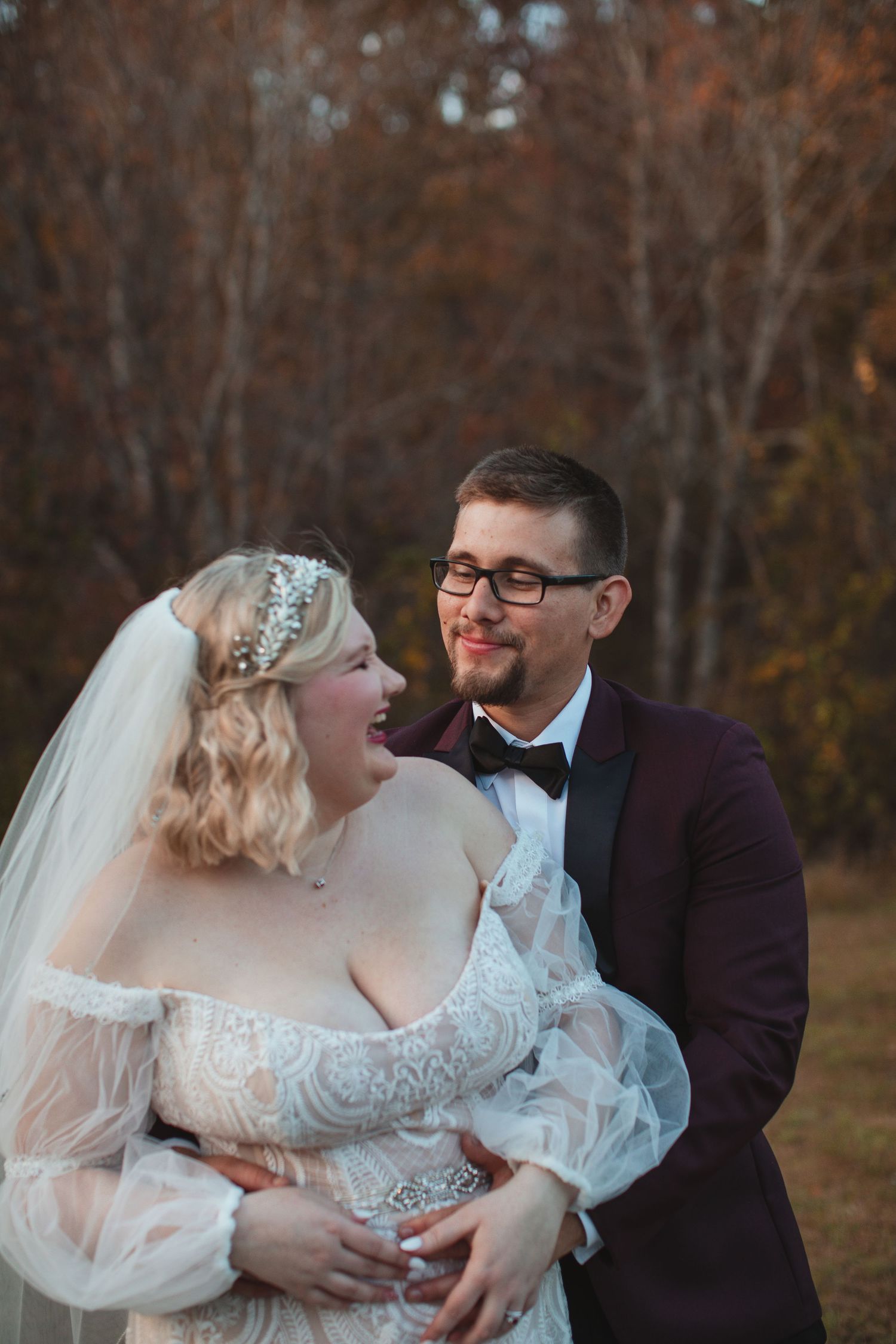 Bride and groom laughing together during their fall wedding portraits