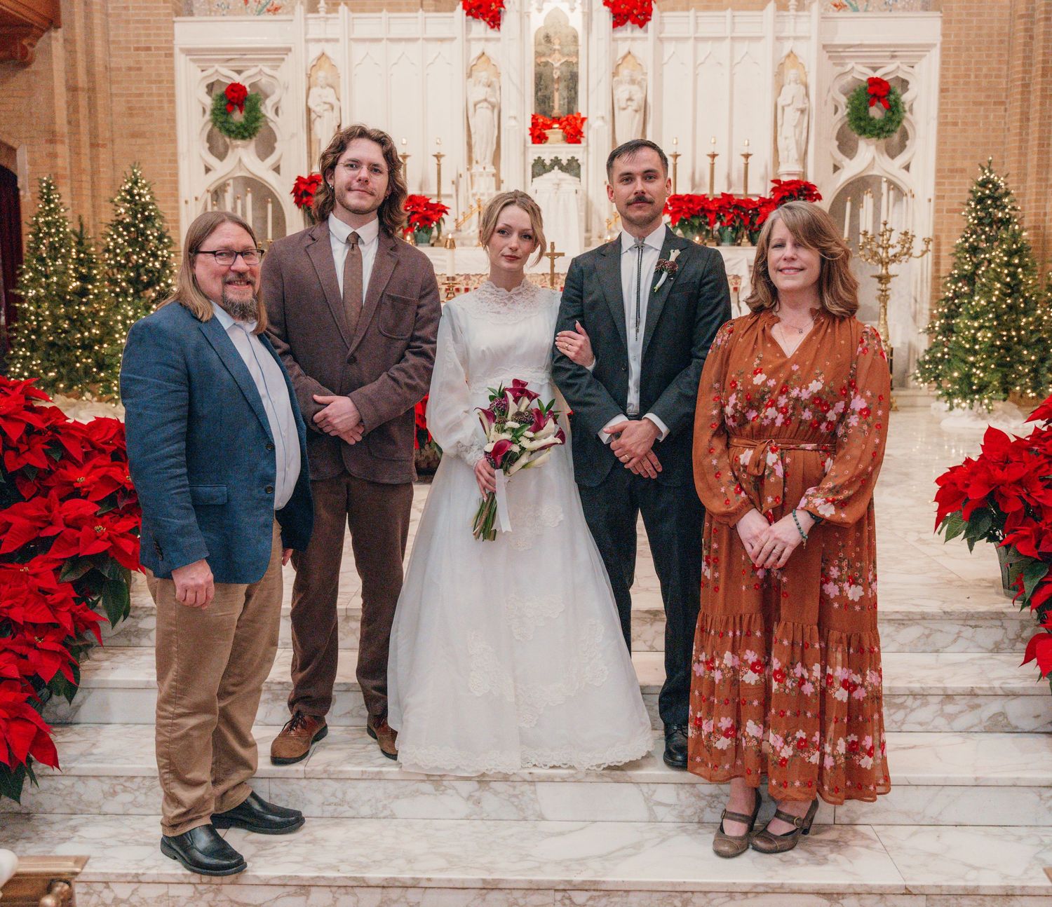 Bride and groom with family at a church altar decorated for Christmas