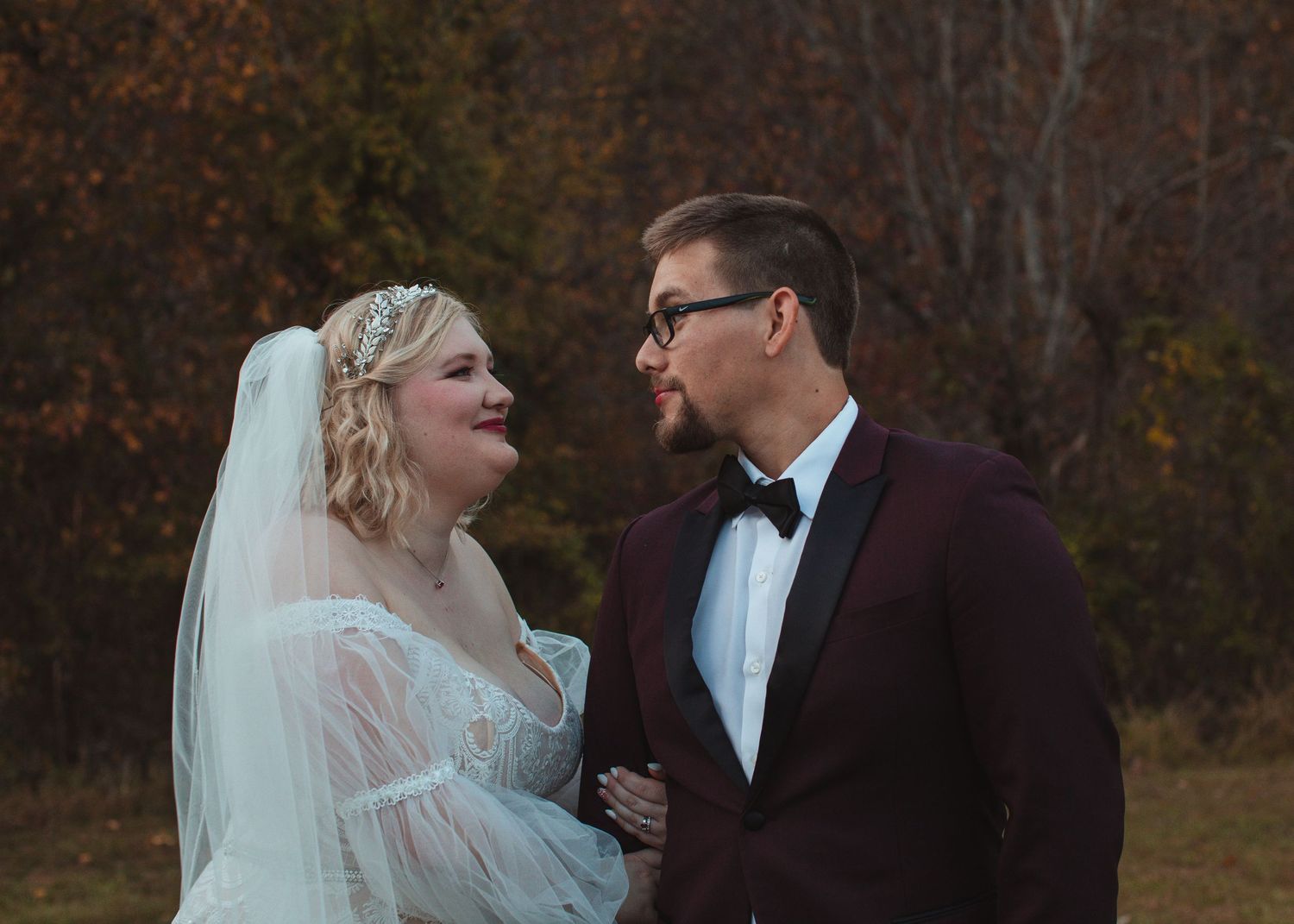 Bride and groom smiling at each other during fall portraits