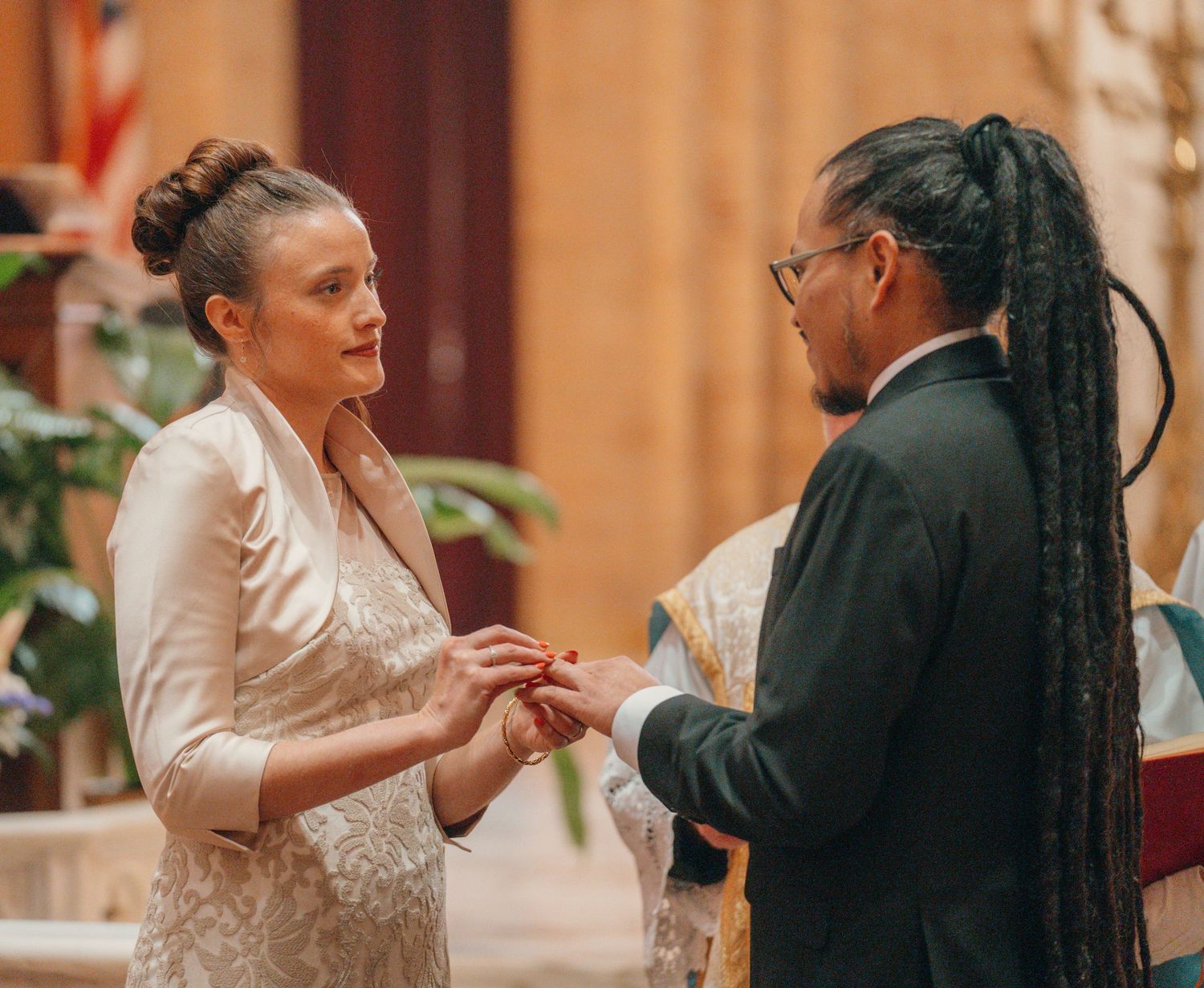 Bride and groom holding hands and smiling while exchanging vows in church