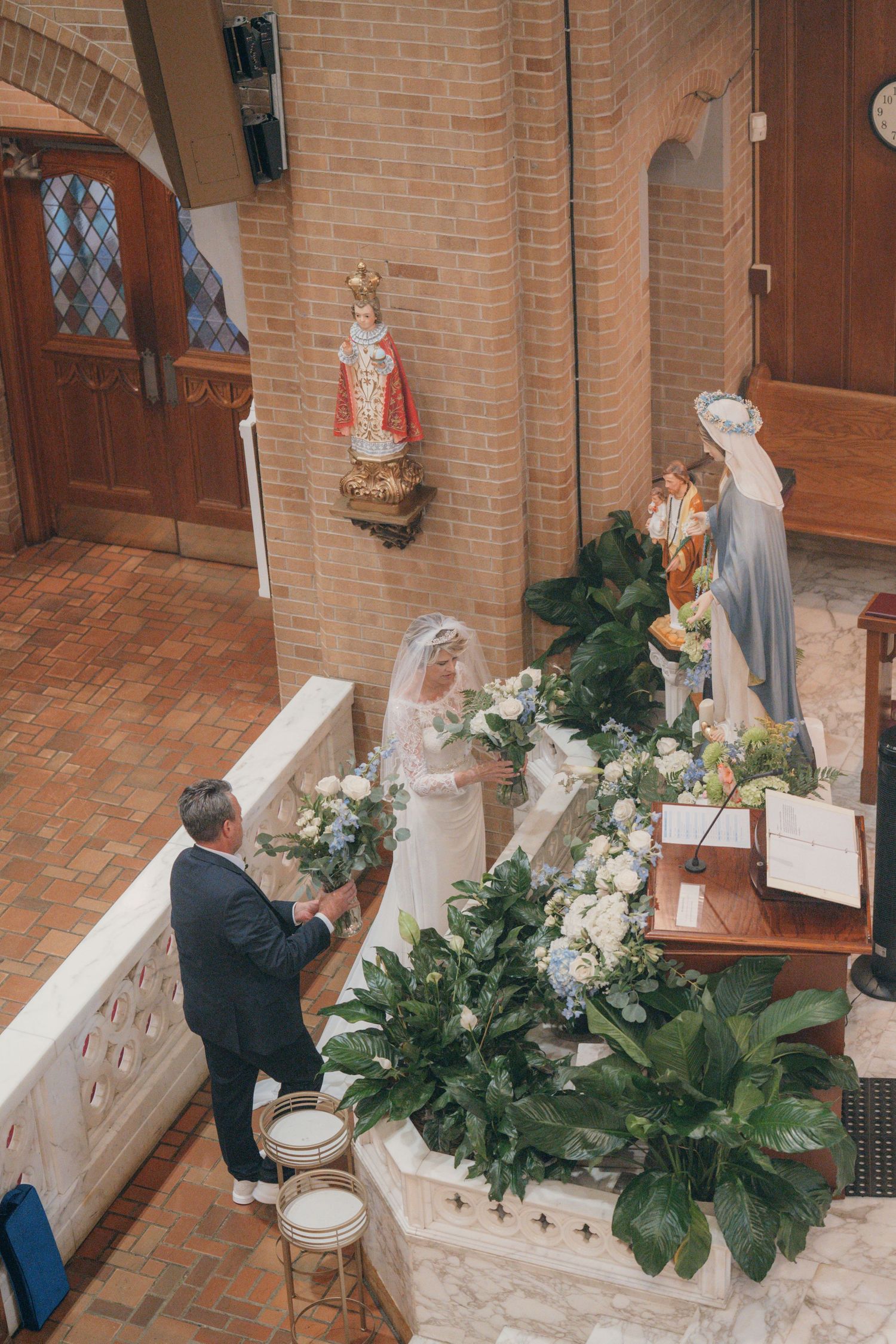Bride and groom offering flowers at the Marian altar during their wedding Mass