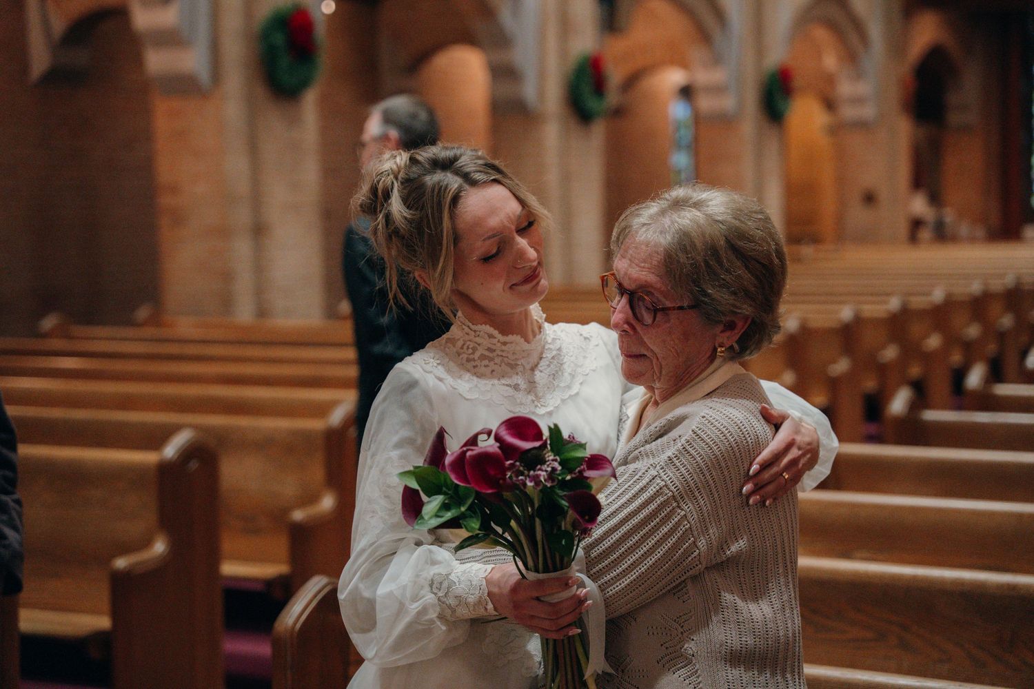 Bride embracing an older relative in the church pews
