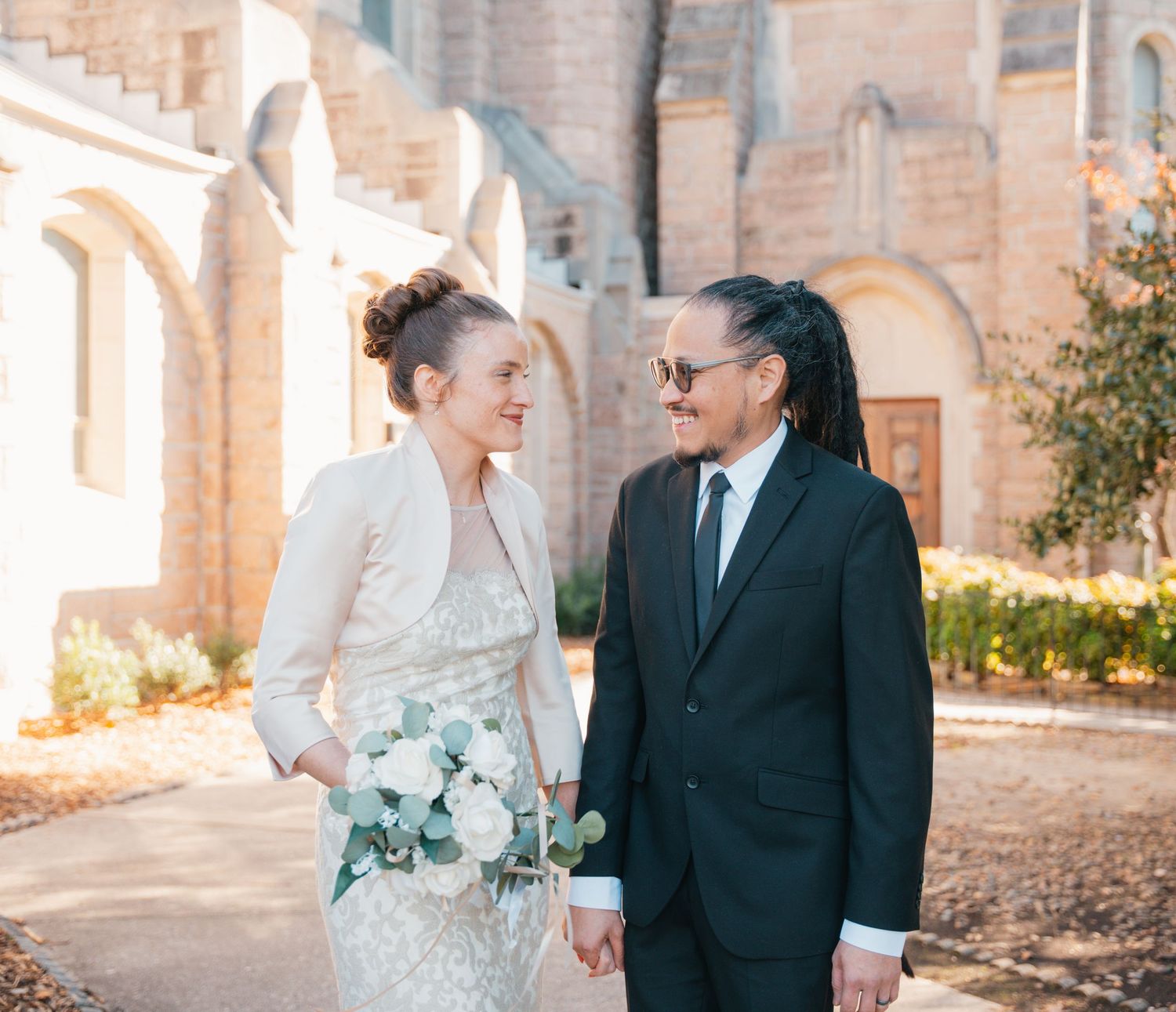 Bride and groom smiling outside a Catholic church after their wedding